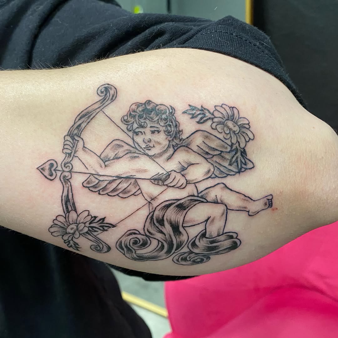 Cherub with bow black and grey tattoo on the forearm by Mack ๐ Utah Tattoos
