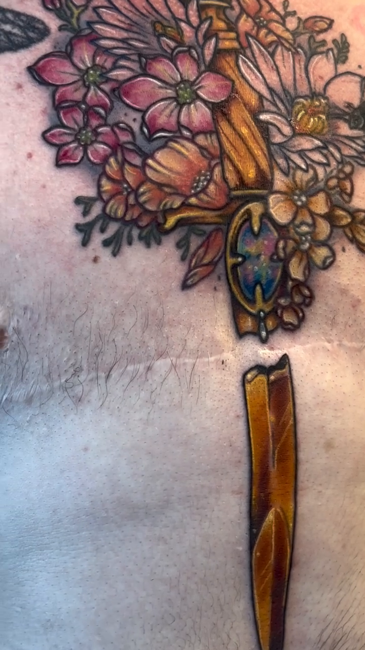 Dagger with flowers tattoo on the torso by Cricket Elijah Cervidae