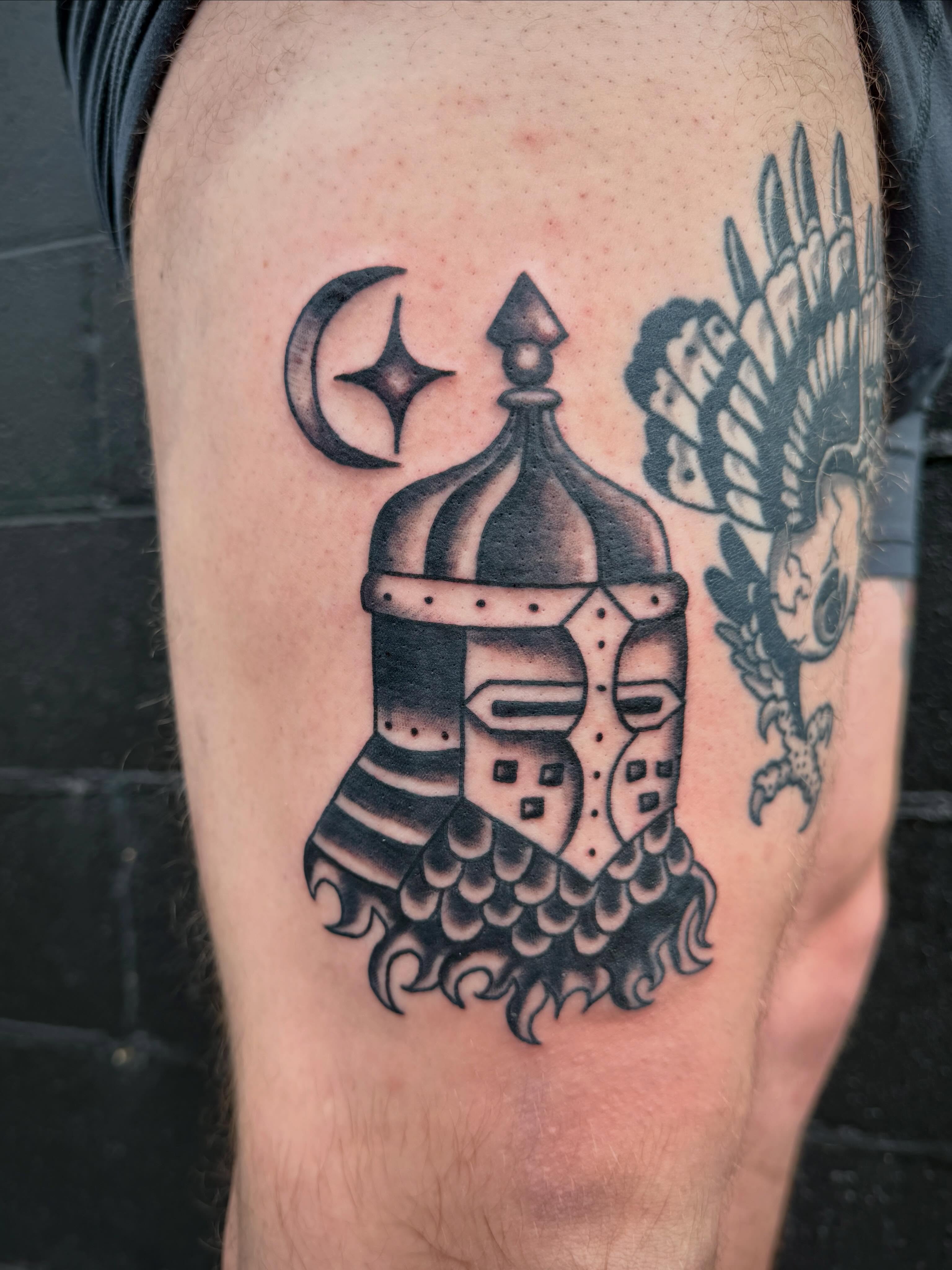 Helmet and eagle black and grey tattoo on the thigh by Ali Calis