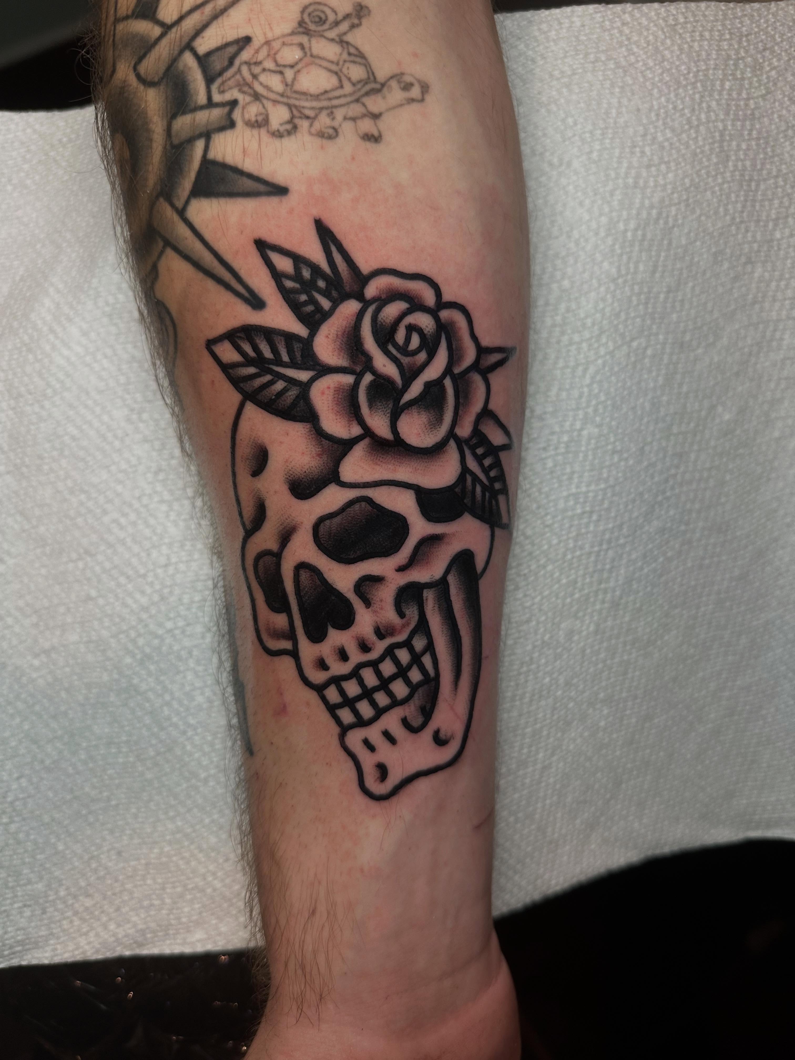 Skull with rose American traditional tattoo on the forearm by Chris Bishop