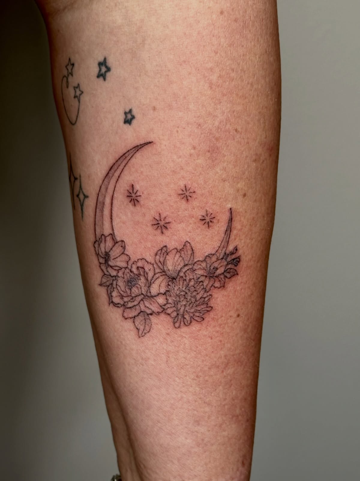 Moon and flowers black and grey tattoo on the forearm by Liz