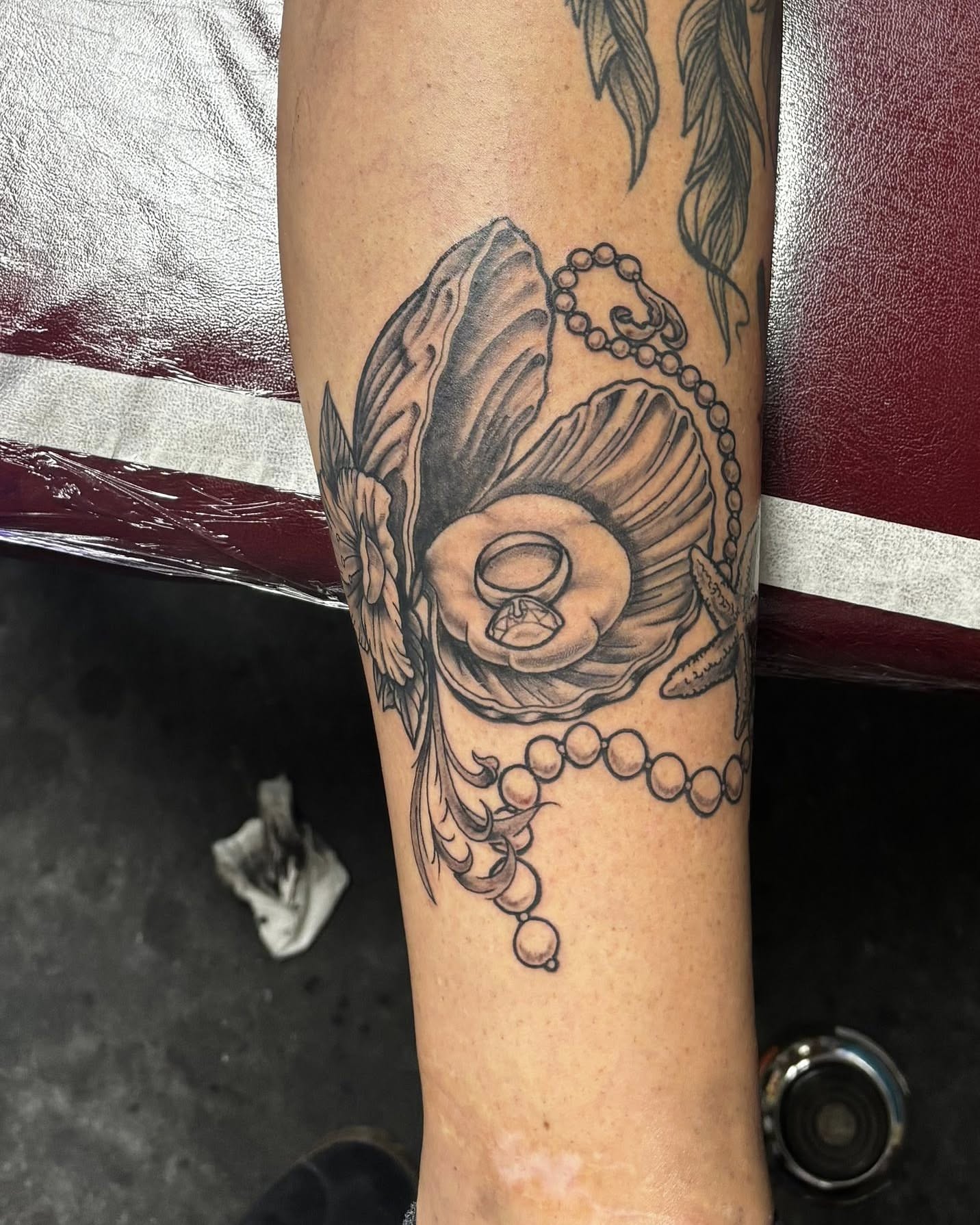 Pearl necklace and flower black and grey tattoo on the forearm by Jeff Zuptich