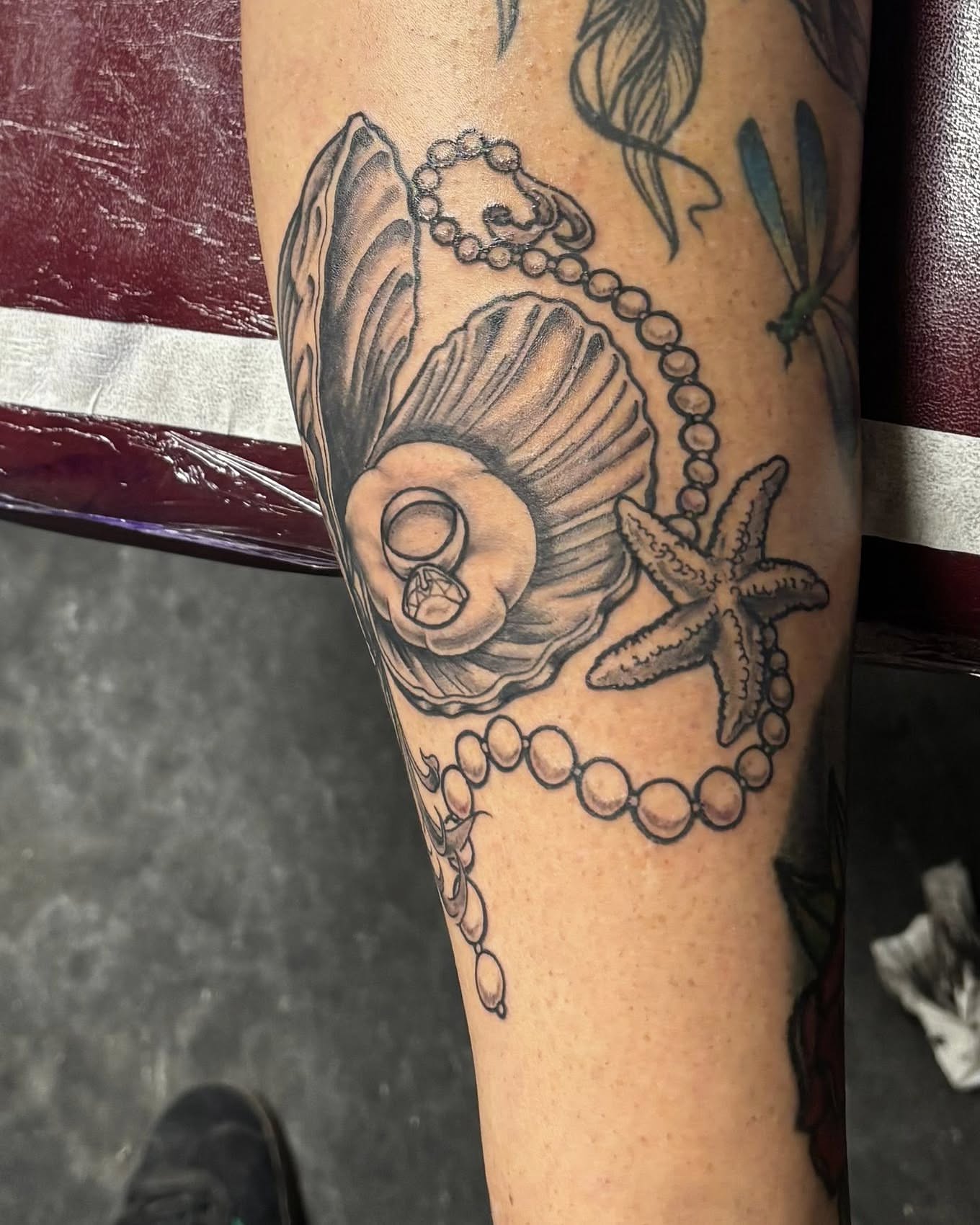 Shell and pearl necklace black and grey tattoo on the forearm by Jeff Zuptich
