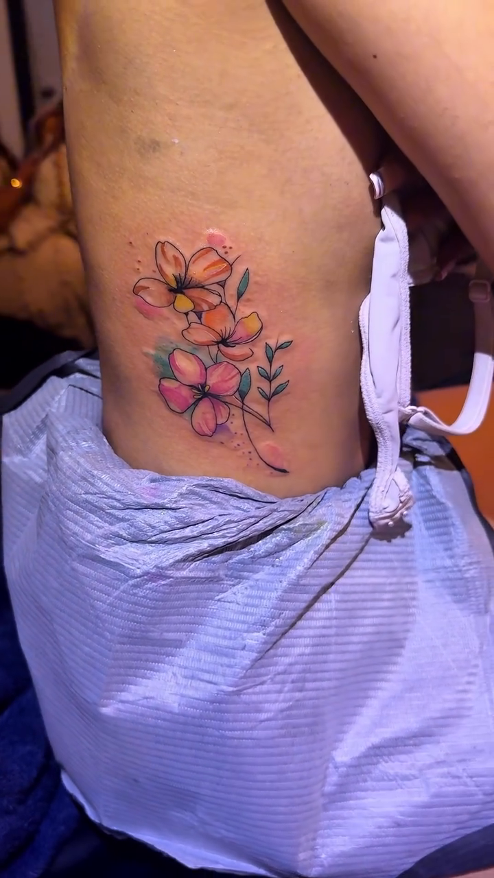 Floral arrangement on ribcage watercolor tattoo on the thigh by 2realink - Tattoo Artist