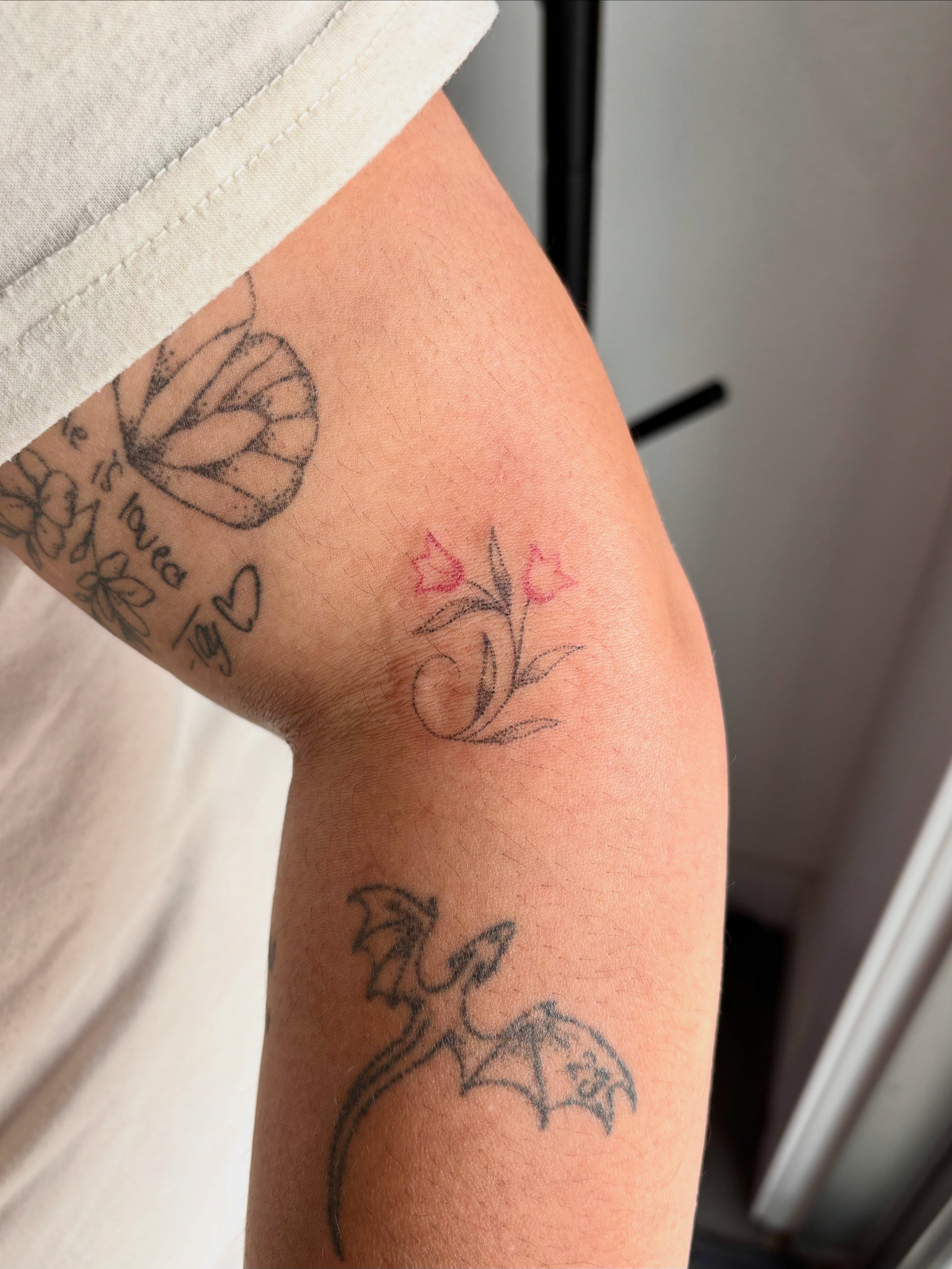 Butterfly, flowers, dragon black and grey tattoo on the forearm by Ashley, Elk Horn, Iowa