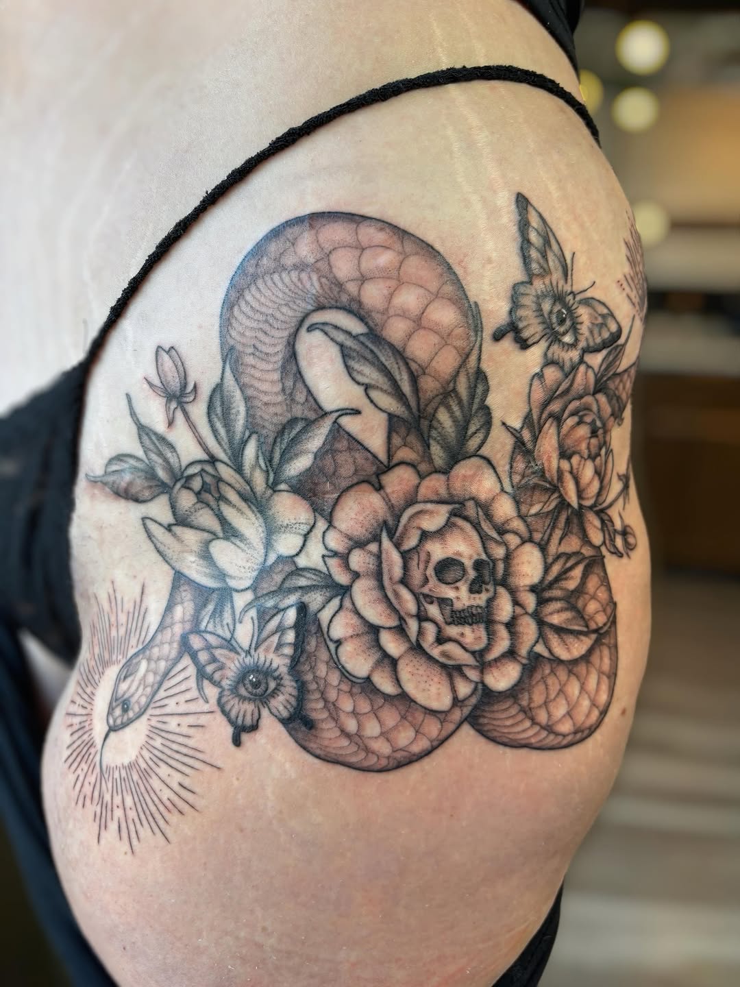 Snake, skull, and flowers fine line tattoo on the shoulder by Bianca Cattapan