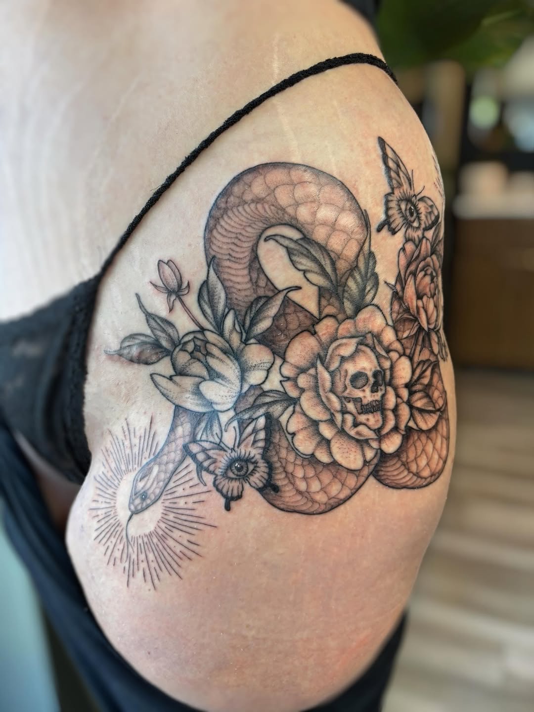 Snake, skull, and flowers fine line tattoo on the shoulder by Bianca Cattapan