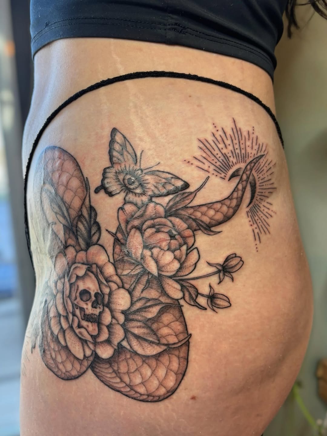 Skull, snake, flowers, and butterfly fine line tattoo on the thigh by Bianca Cattapan