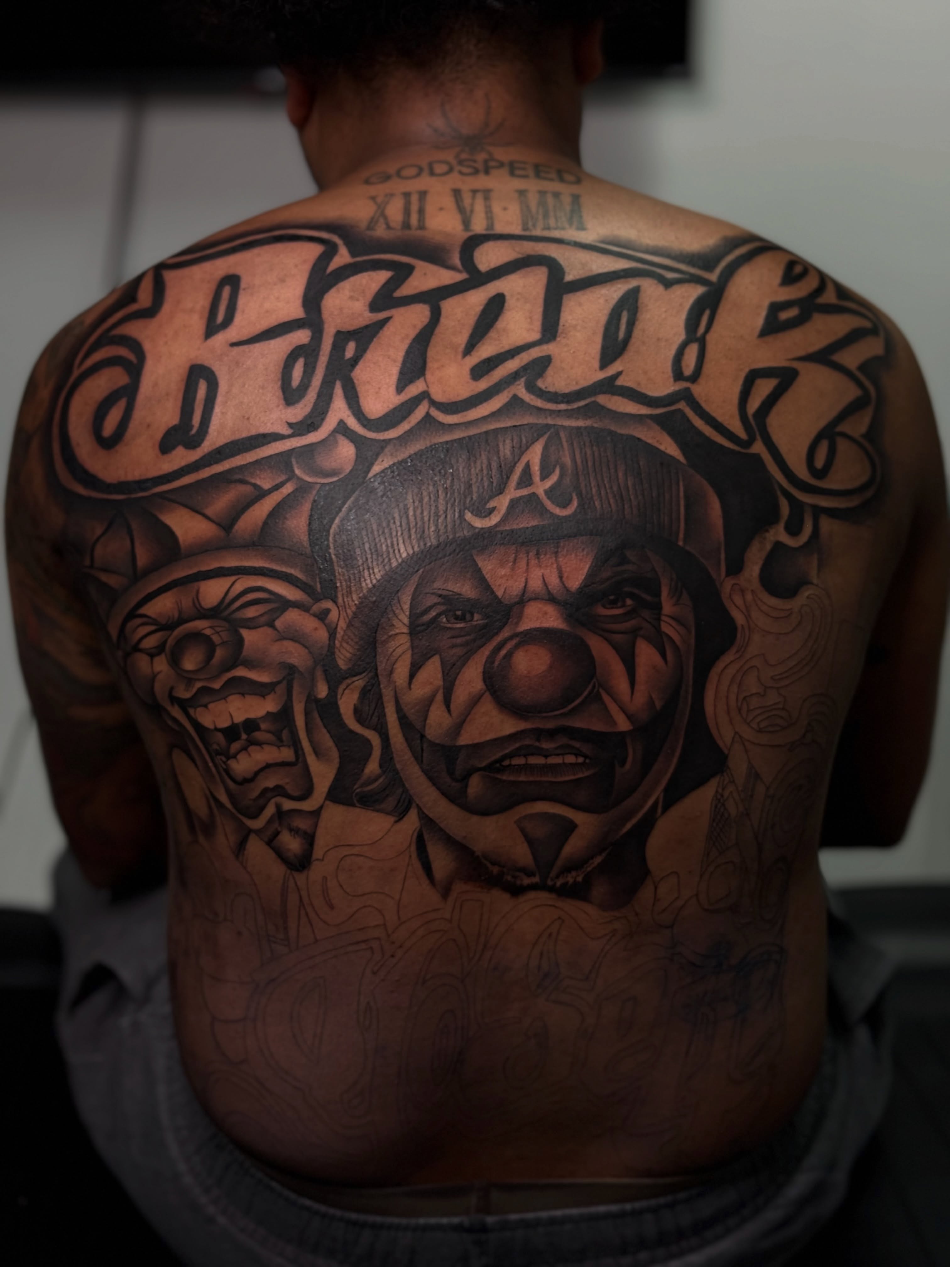 Clown and mask realism tattoo on the back by Savannah Tattoo Artist