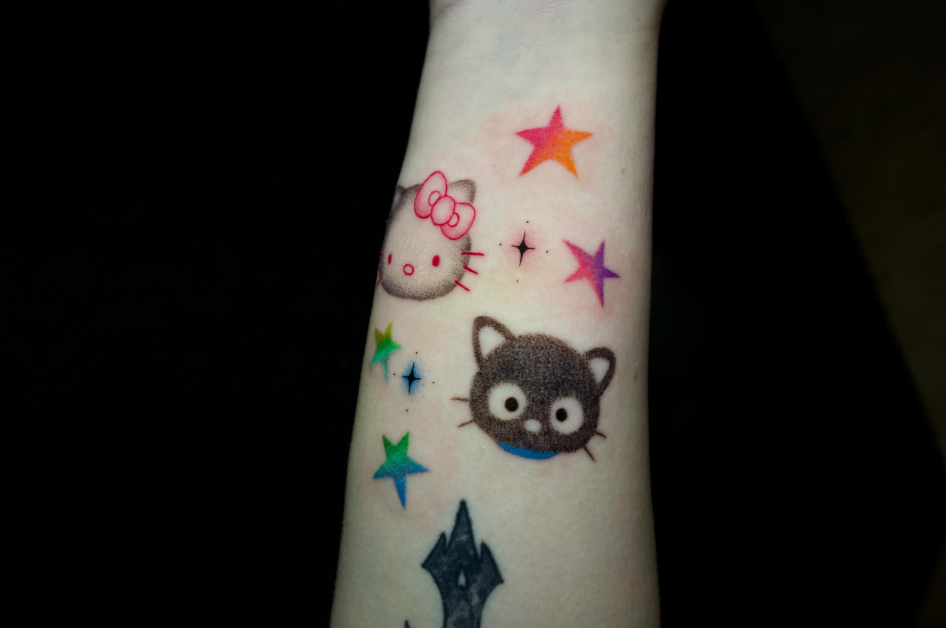 Hello Kitty and Cheshire Cat dotwork tattoo on the forearm by dani