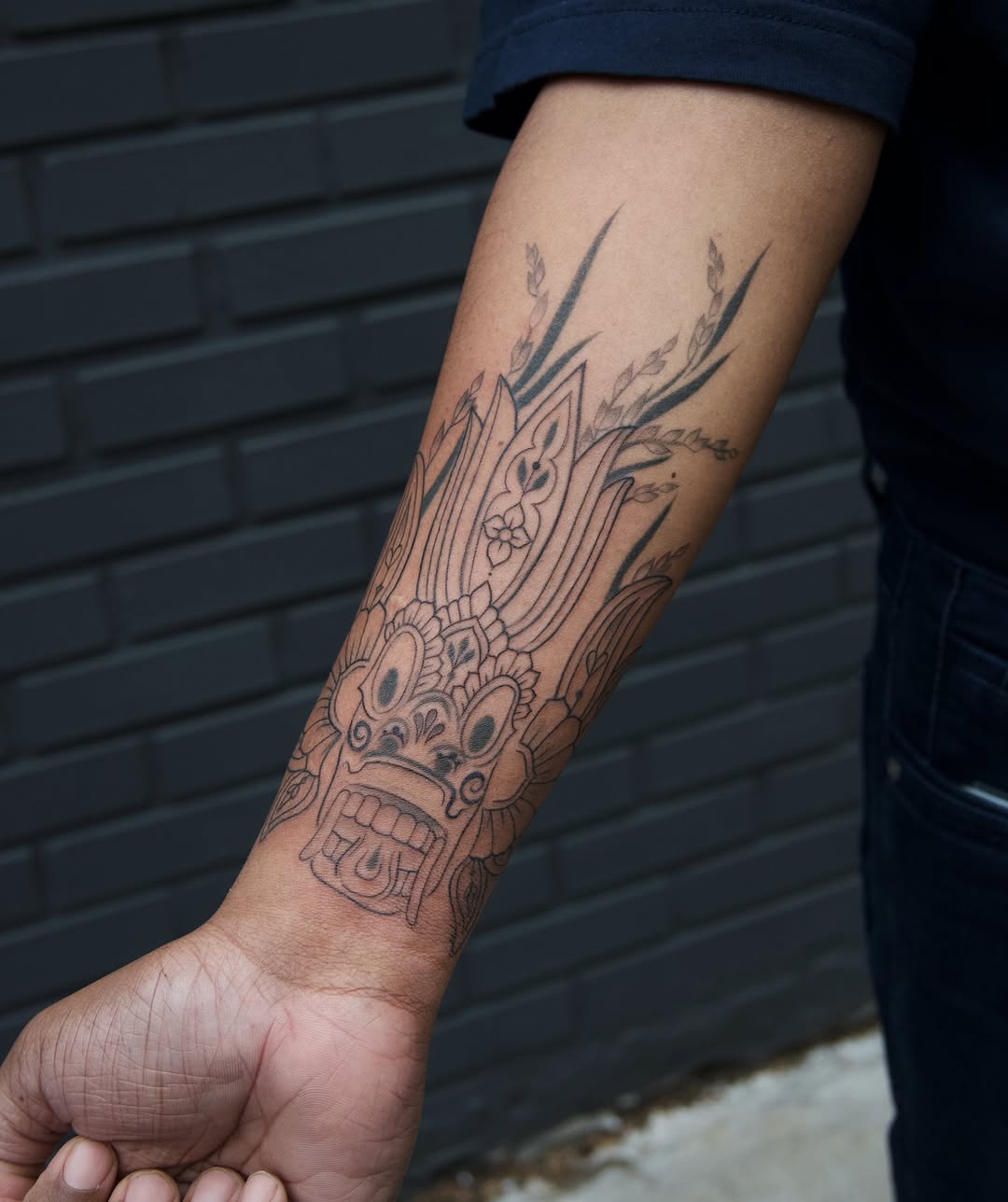 Mask black and grey tattoo on the forearm by Sabreena Haque