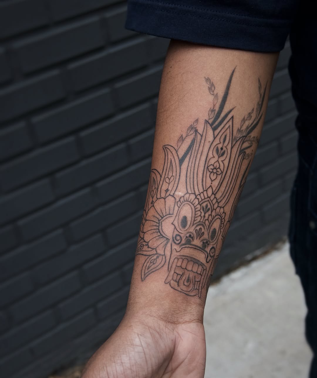 Mask black and grey tattoo on the forearm by Sabreena Haque