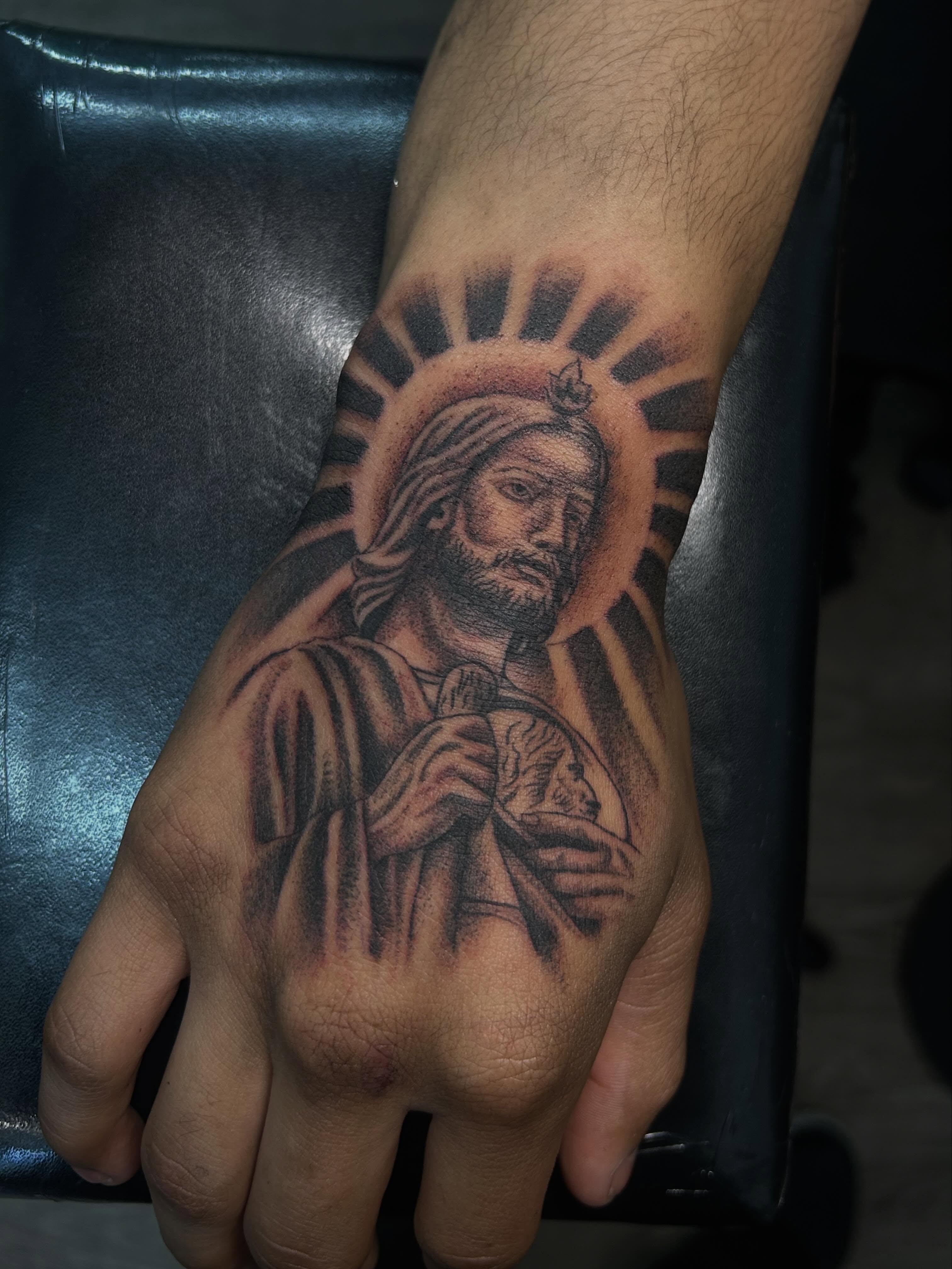 Religious figure black and grey tattoo on the hand by Ximena Favela