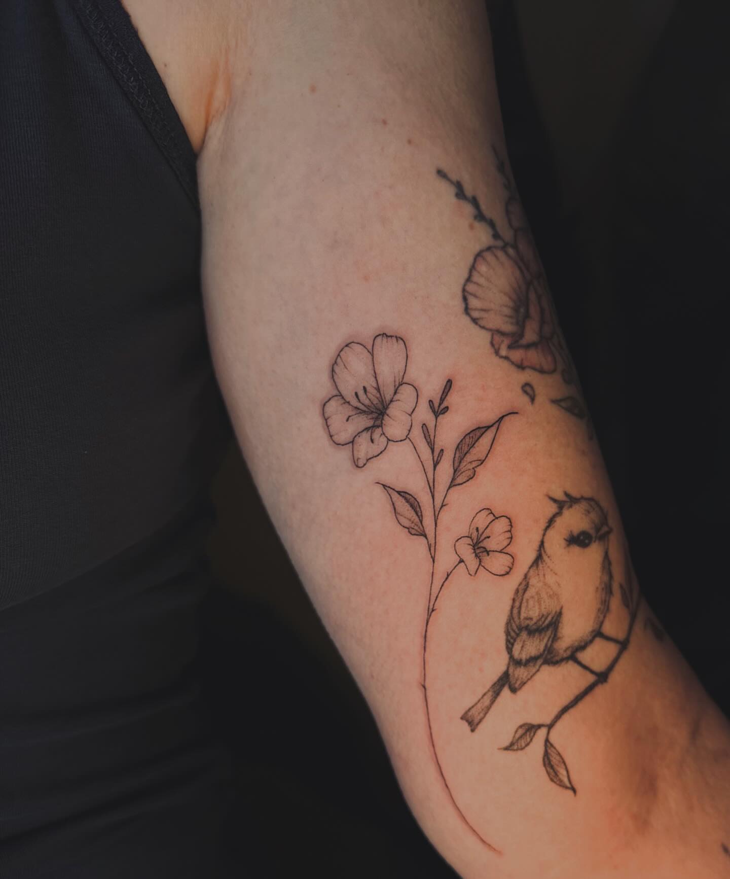 Bird and flowers black and grey tattoo on the forearm by Ashley Pilgreen