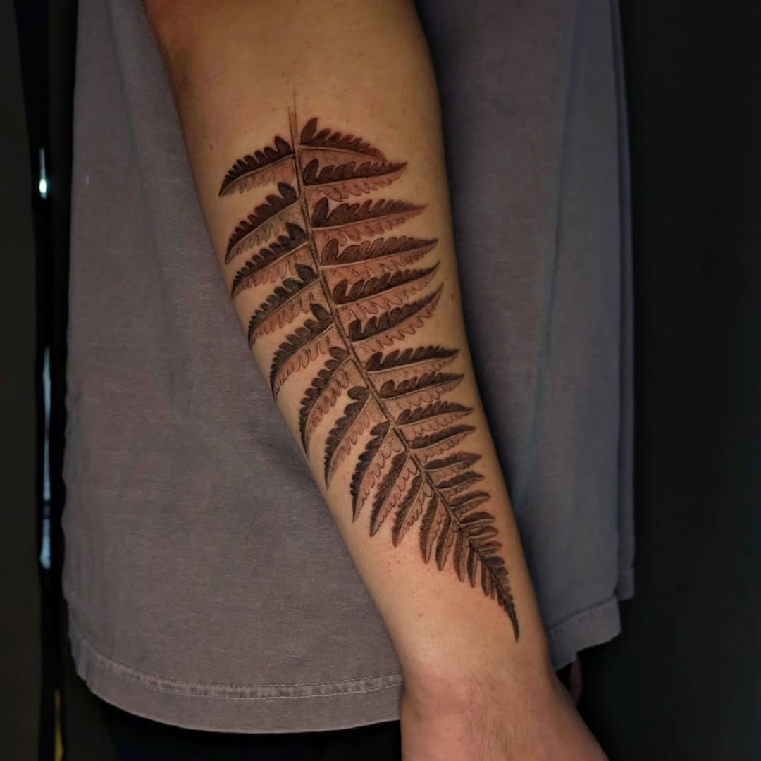 Fern black and grey tattoo on the forearm by Jasmine Dillon