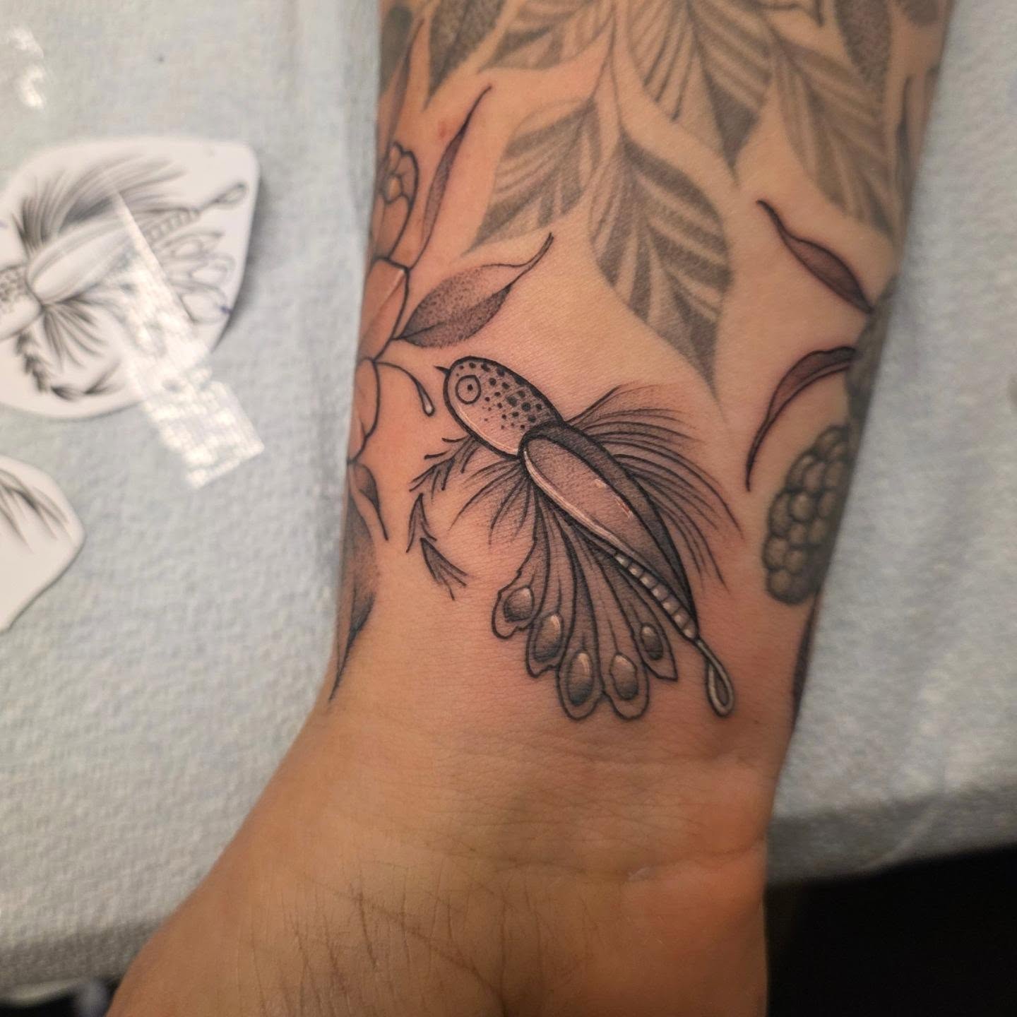 Fish and leaves dotwork tattoo on the forearm by Dani Bond