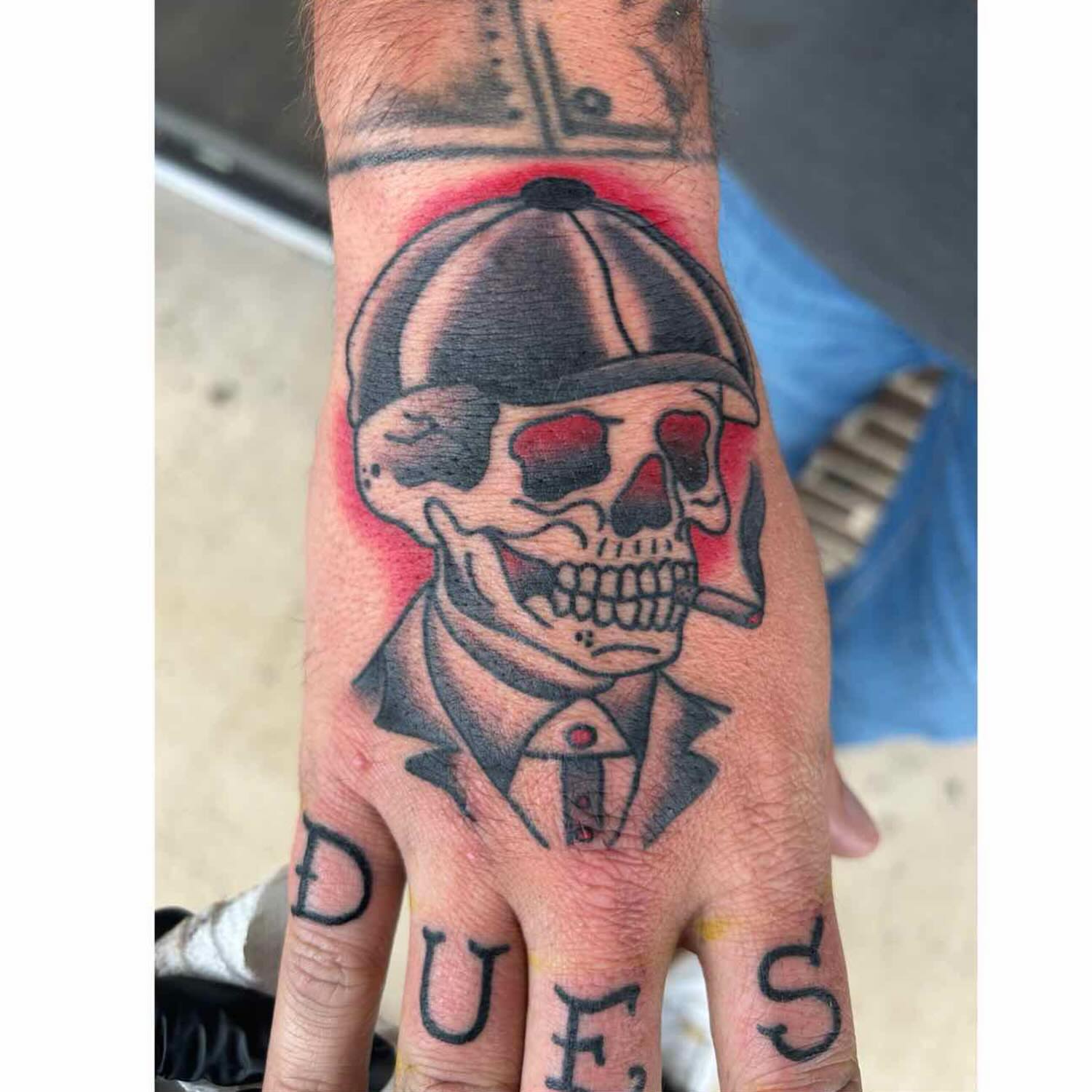 Skull wearing hat American traditional tattoo on the hand by Zach Andrews