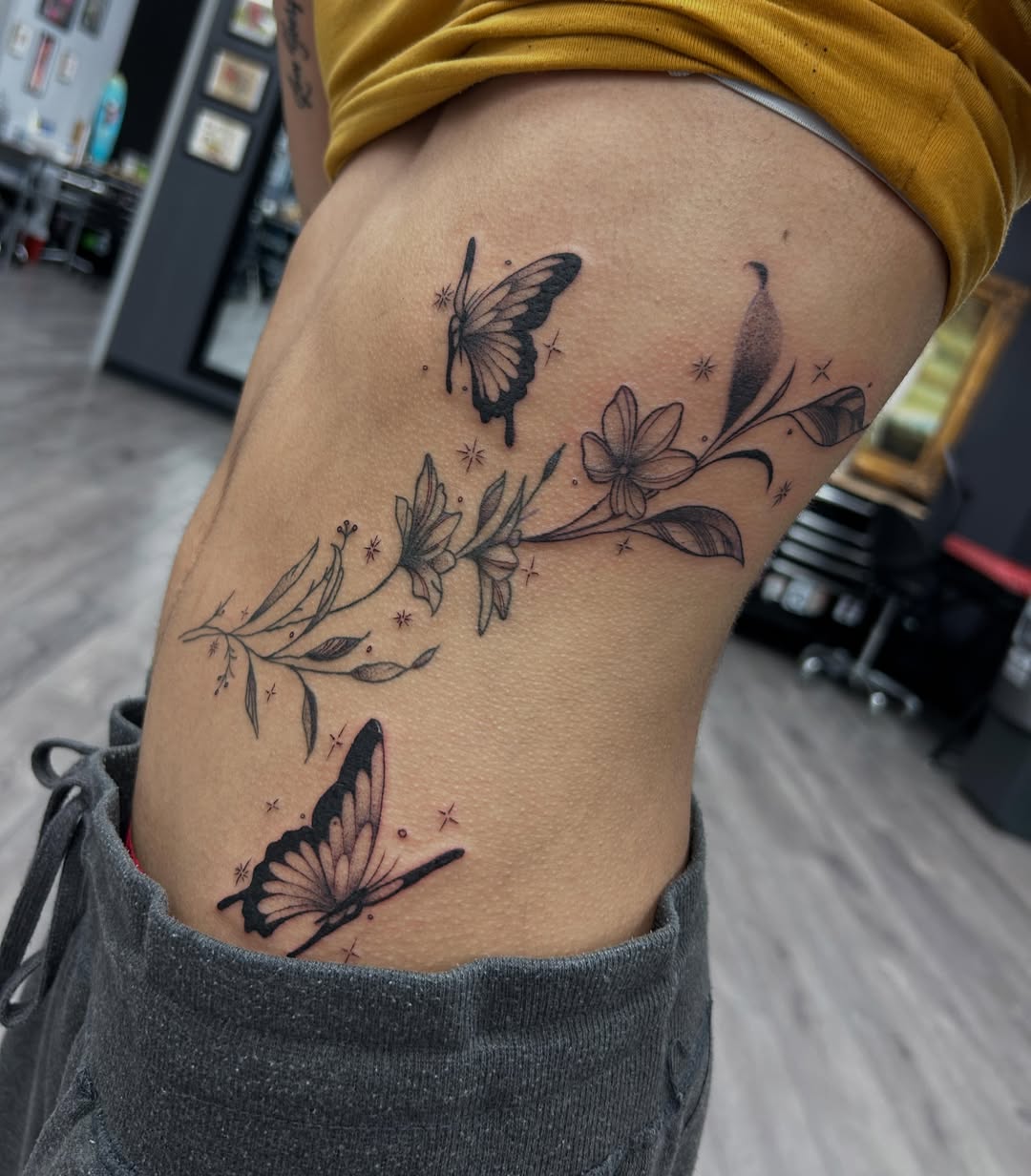 Butterfly and floral black and grey tattoo on the thigh by Livy baby