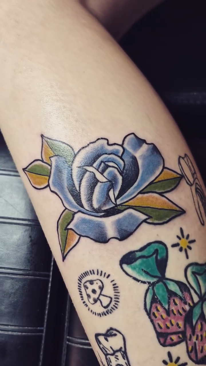Blue rose with candy and teeth neo-traditional tattoo on the forearm by Bobby H