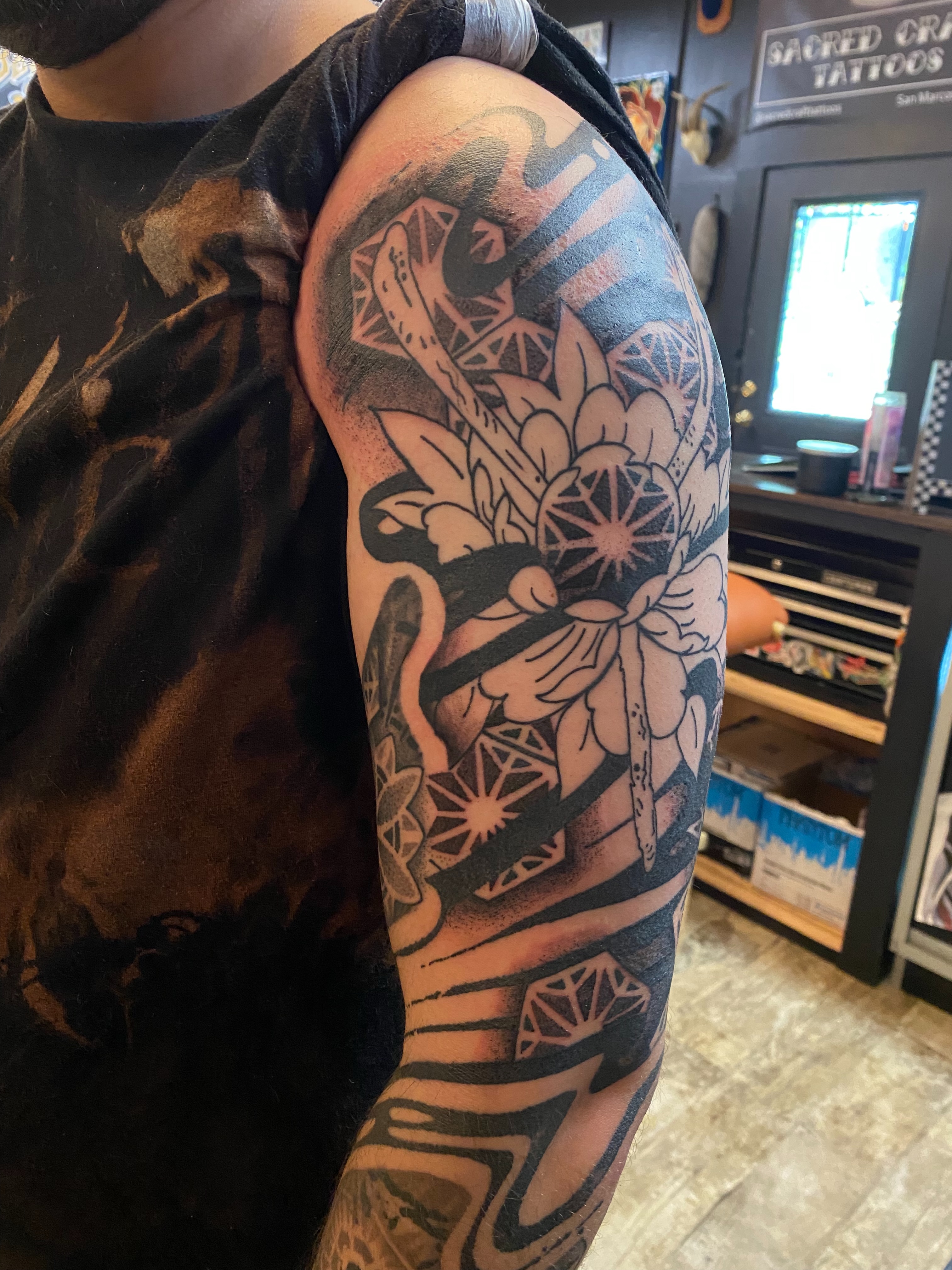Lotus flower geometric tattoo on the upper arm by Emily Miller