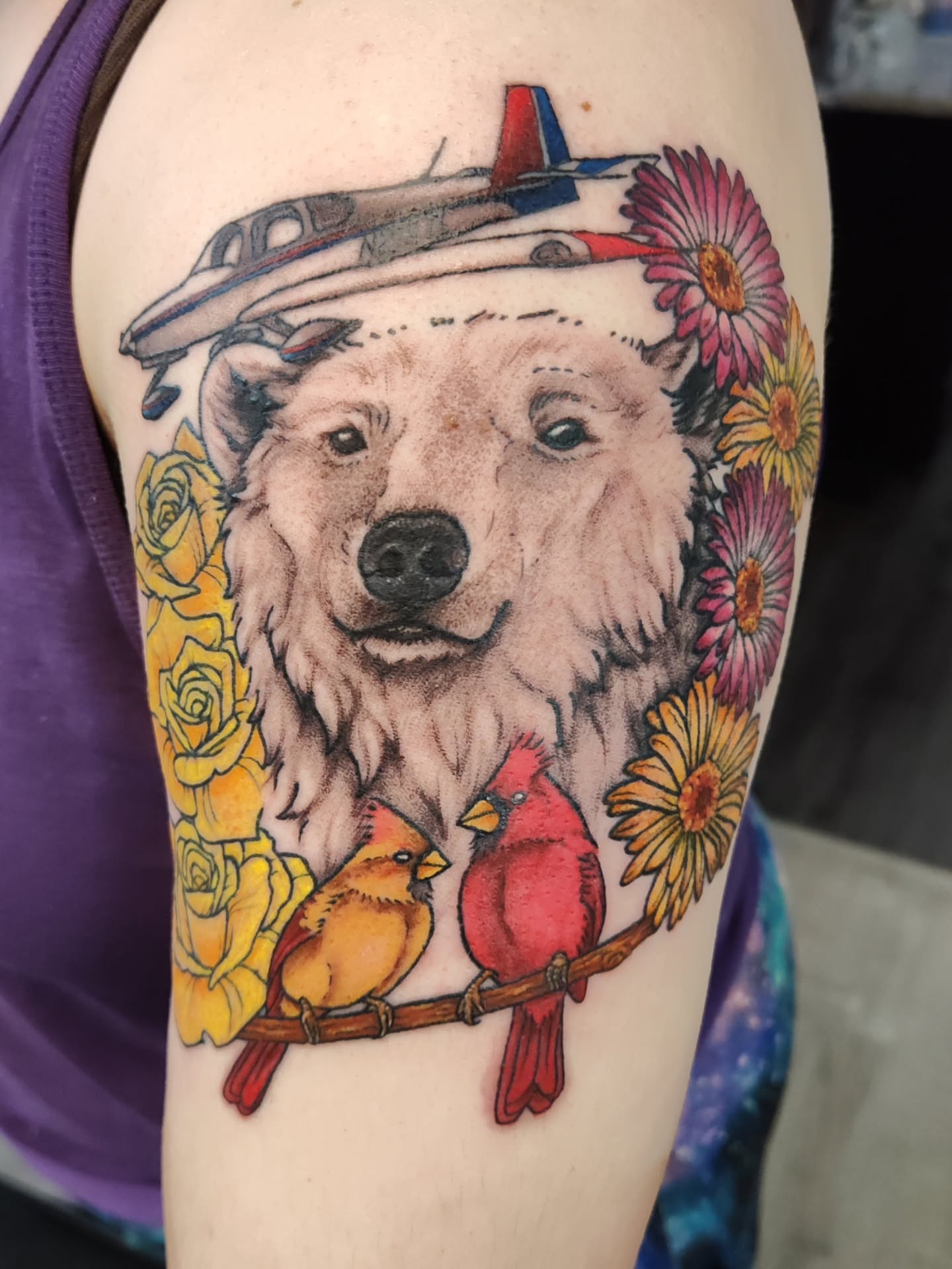 Polar bear with birds and flowers realism tattoo on the upper arm by Mercury