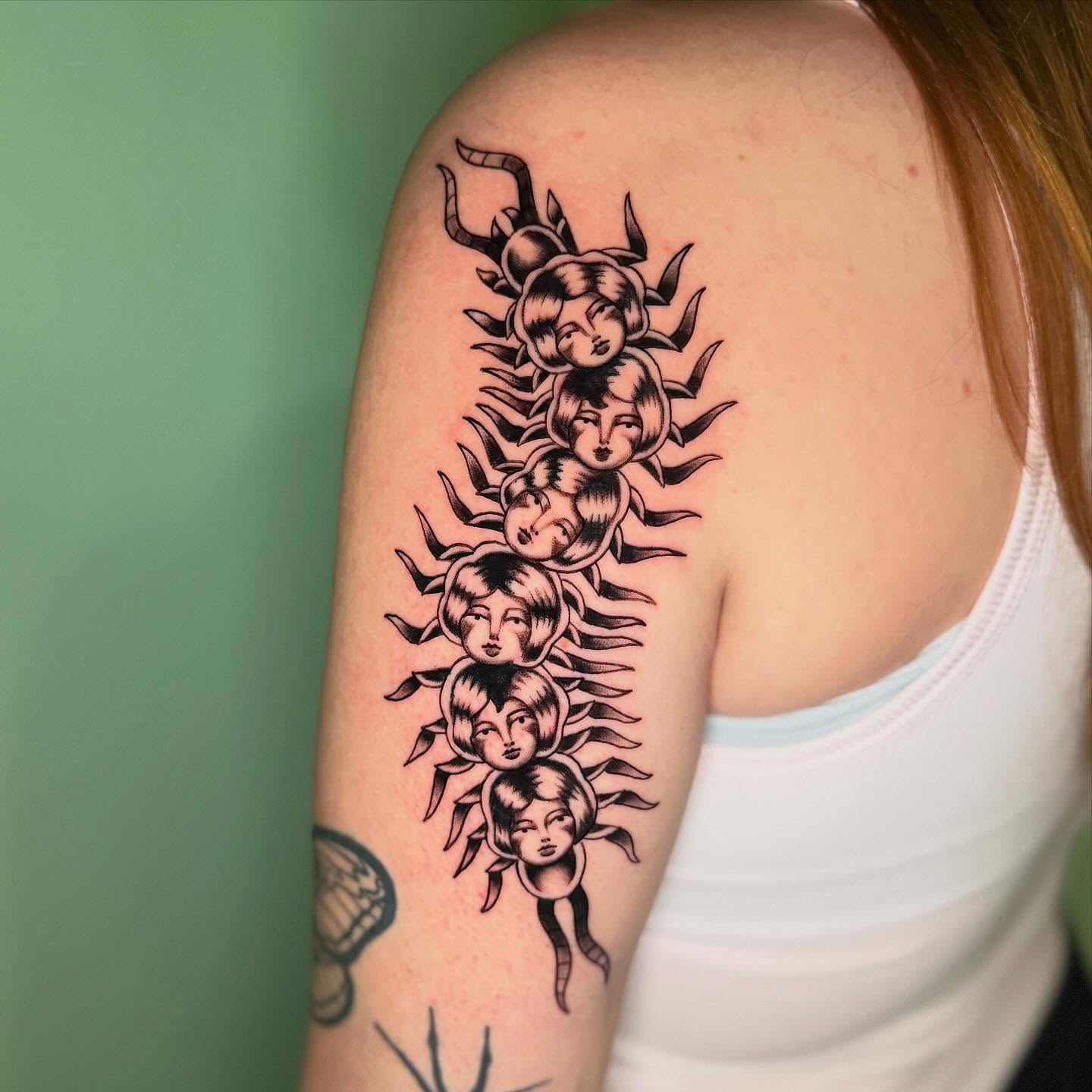 Centipede with faces black and grey tattoo on the shoulder by charlie