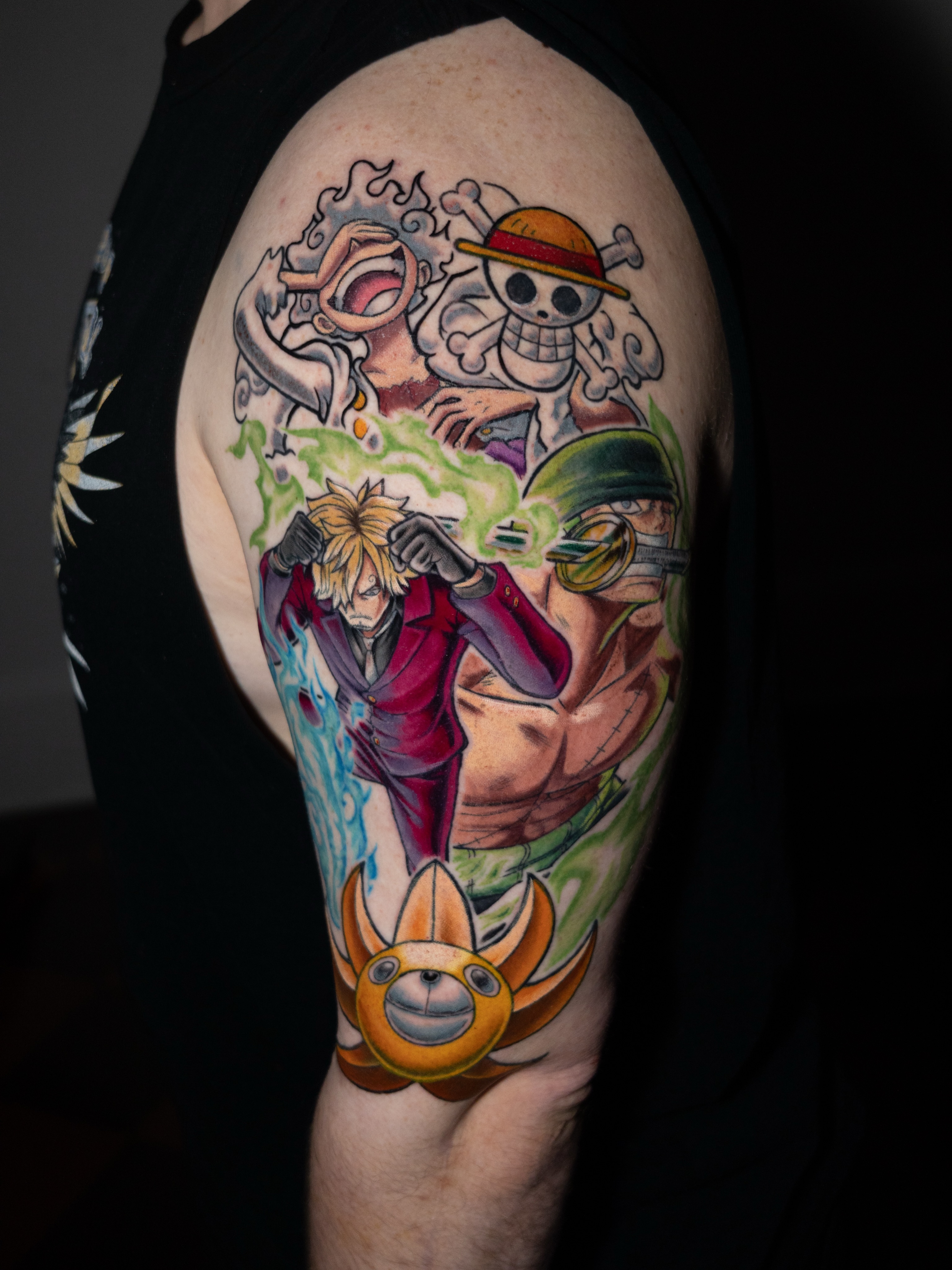 Anime characters anime tattoo on the upper arm by Tracci King