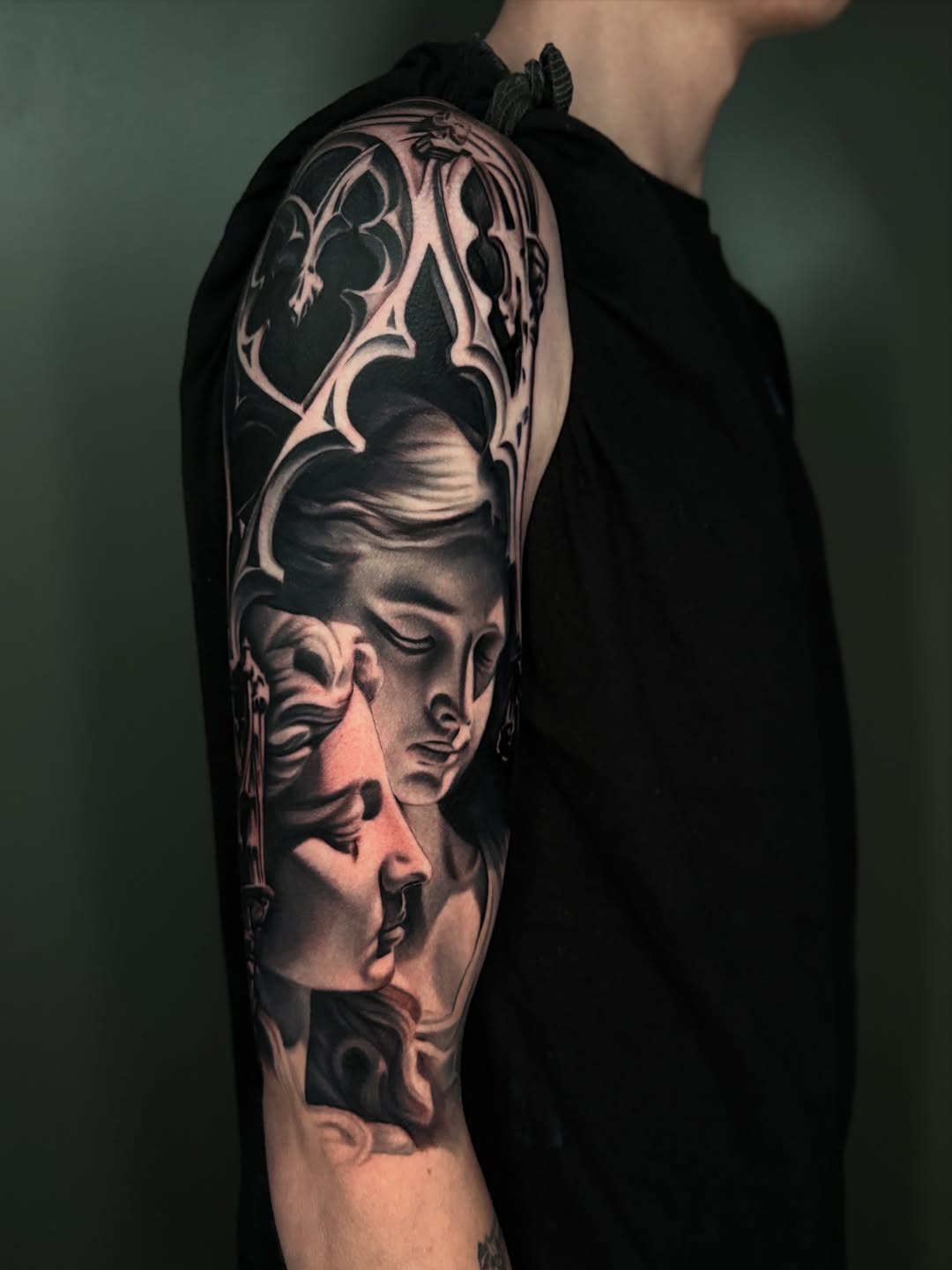 Two faces in gothic architecture realism tattoo on the upper arm by Dakota Case