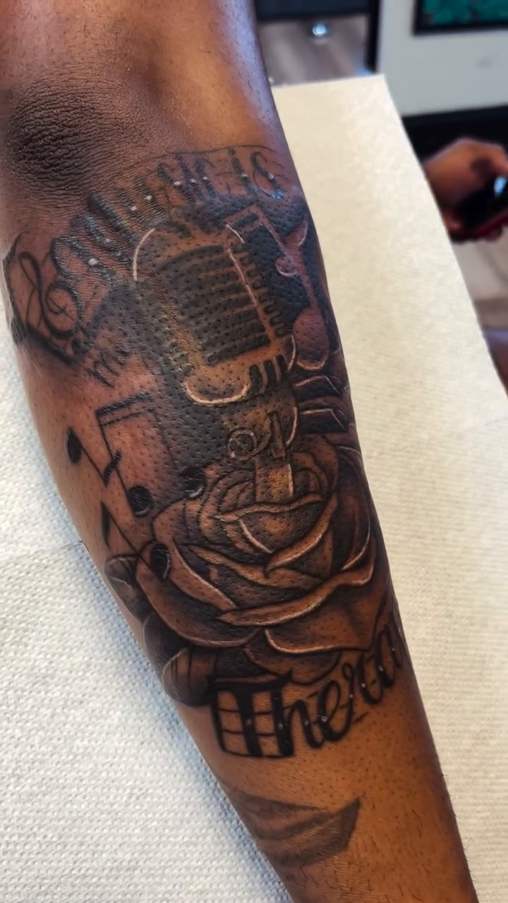 Microphone, rose, and lettering realism tattoo by Danielle Lorandeau