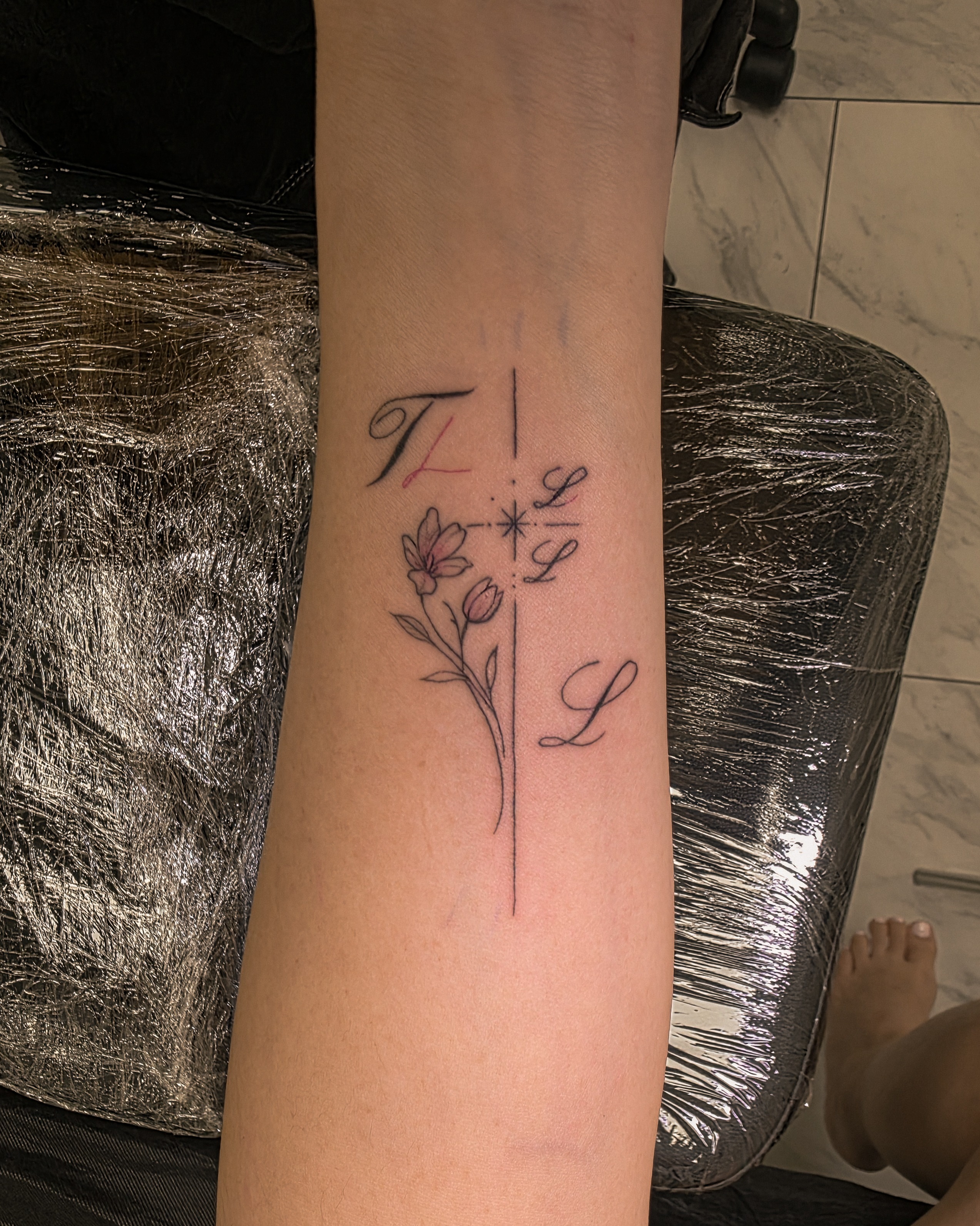 Cross with floral design fine line tattoo on the forearm by Richmond tattoo shop, Richmond, Texas