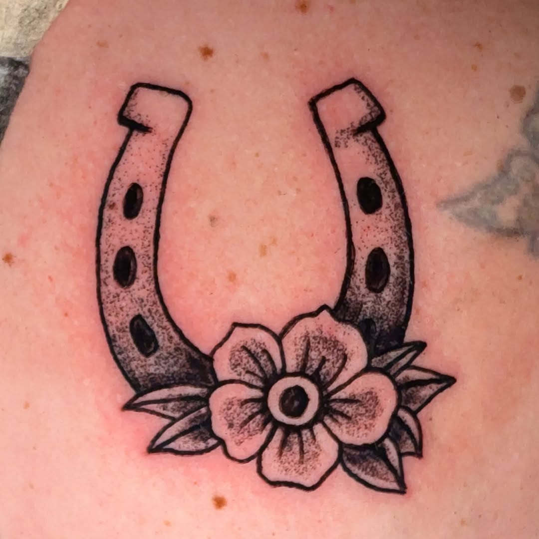 Horseshoe with flower American traditional tattoo on the chest by Matt Mahl