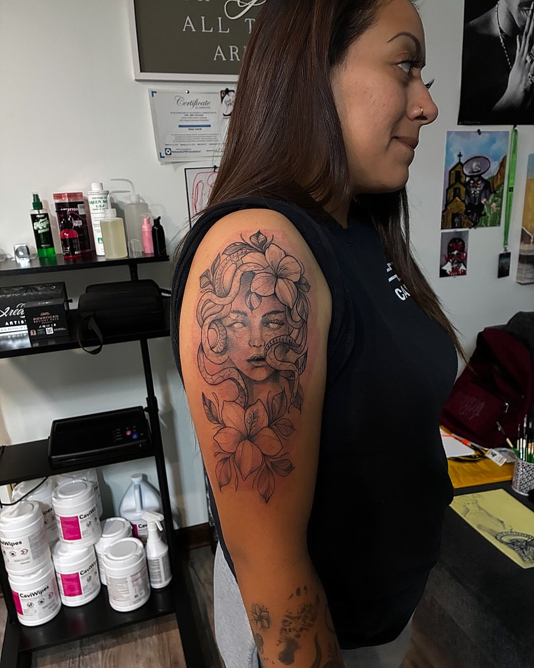 Woman with flowers black and grey tattoo on the upper arm by Uno Inks