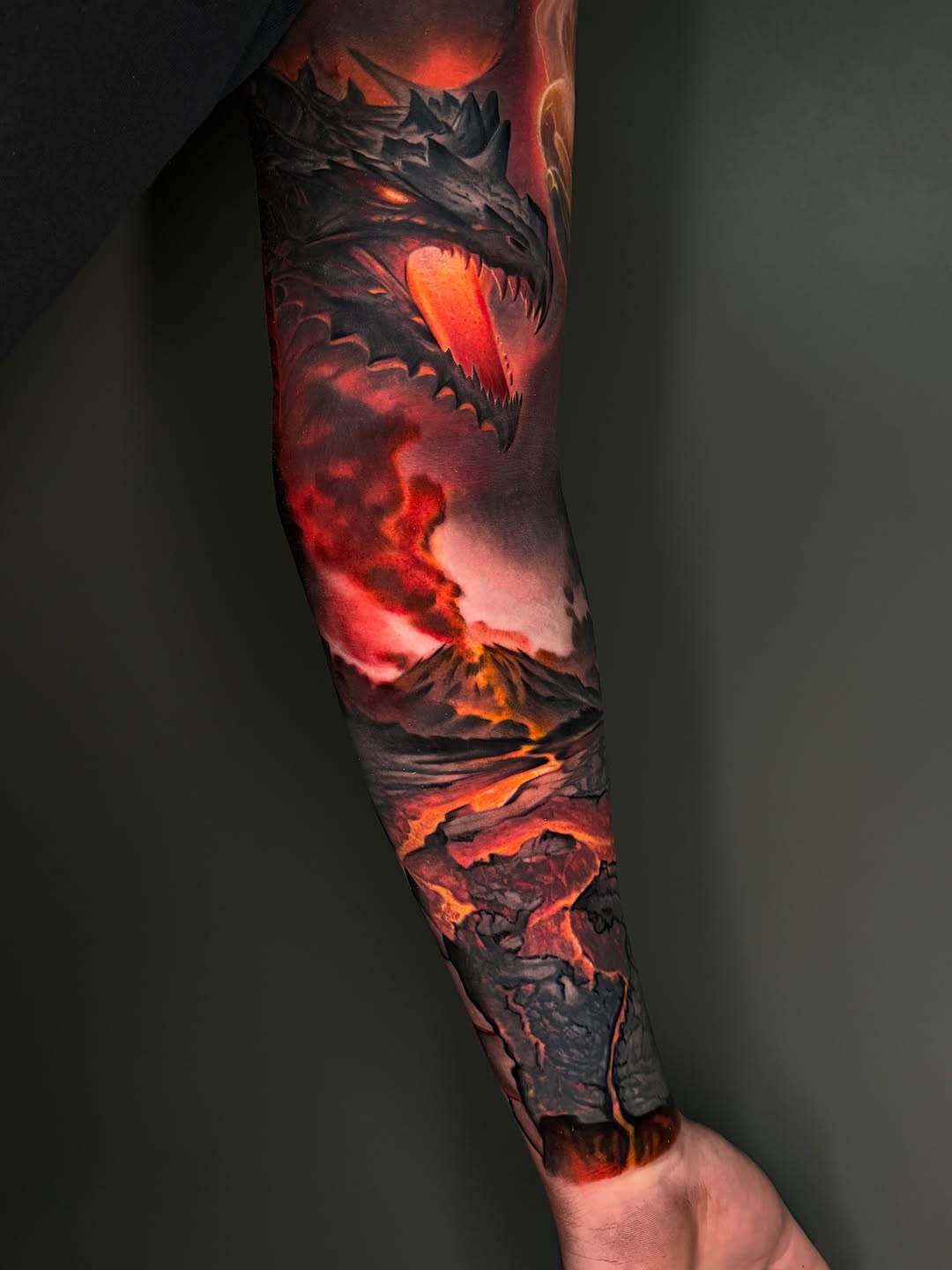 Dragon and volcano landscape realism tattoo on the forearm by Dakota Case