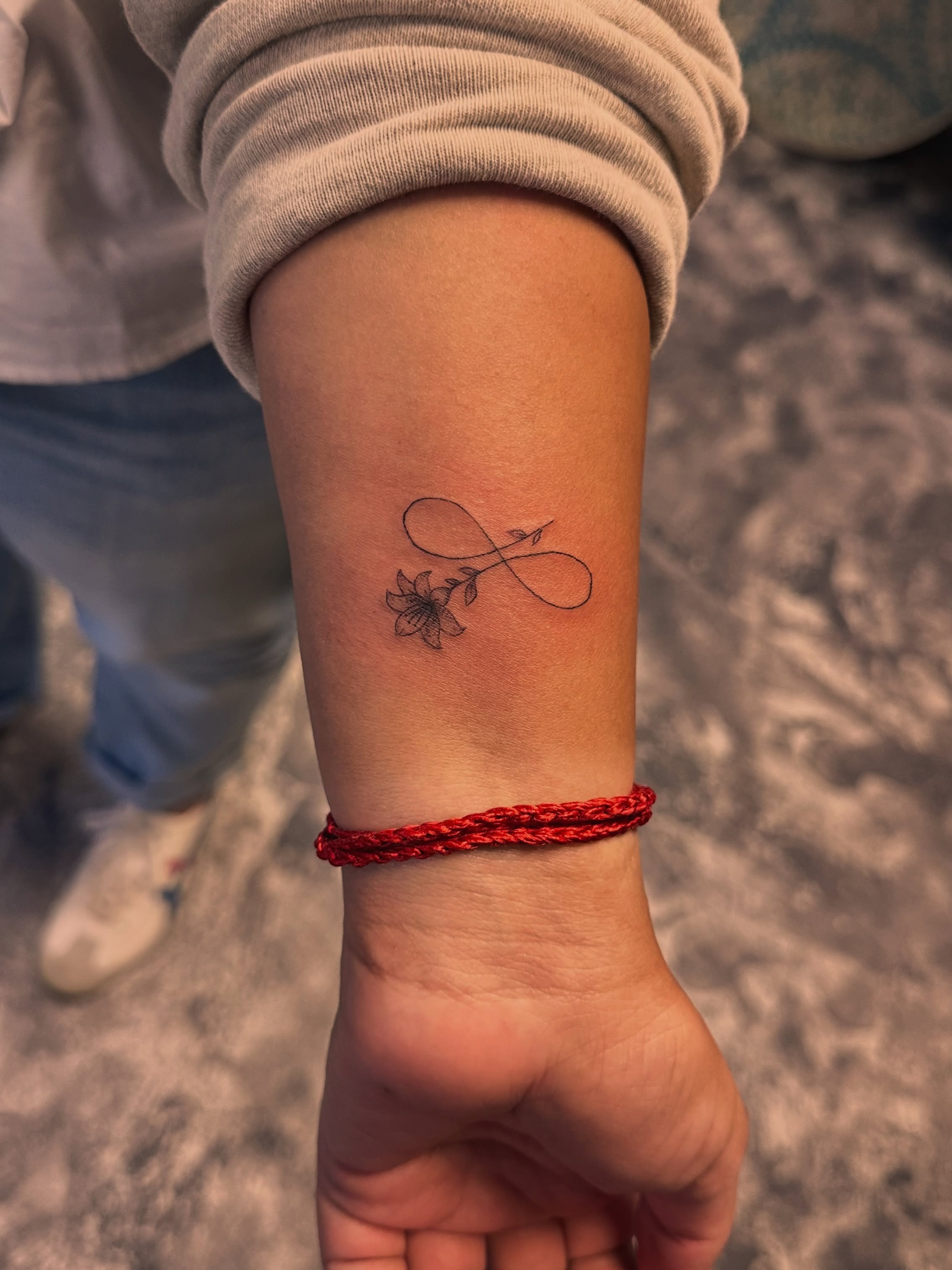 Infinity symbol with flower fine line tattoo on the forearm by Lunette : a little moon as simple as that