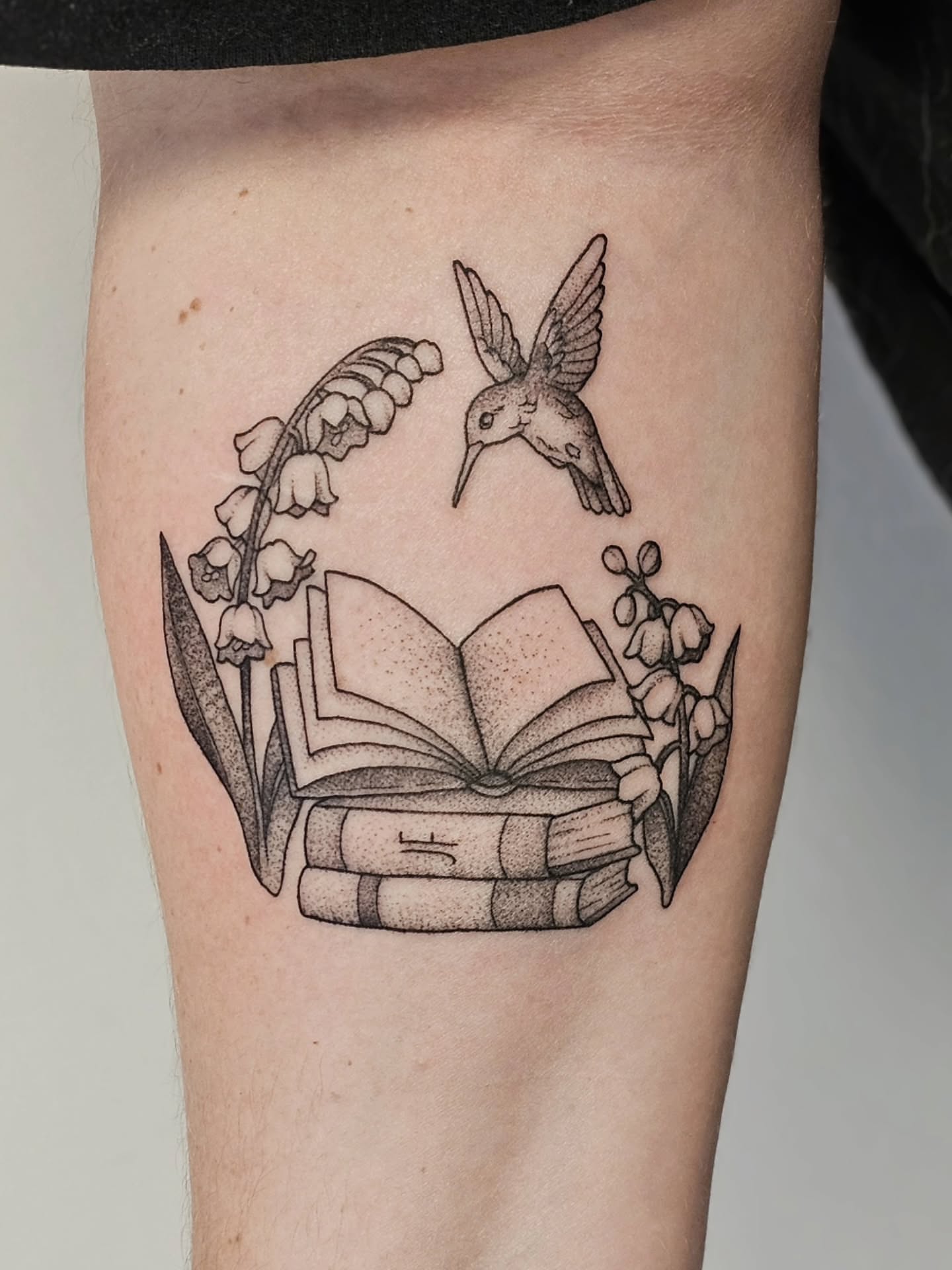 Hummingbird and books dotwork tattoo on the thigh by Kylie Lund