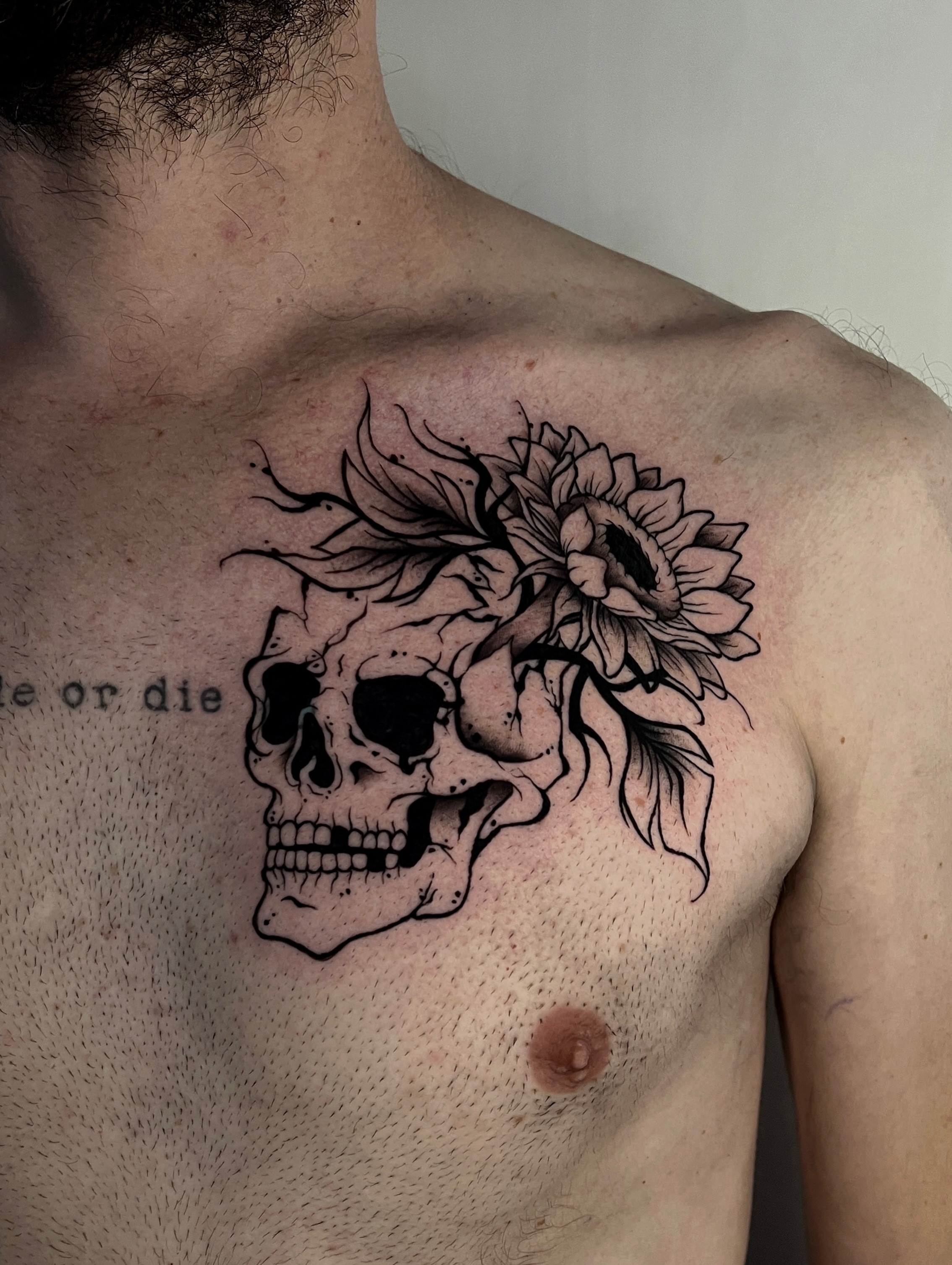 Skull with sunflower black and grey tattoo on the chest by Rebel milly Tattoo