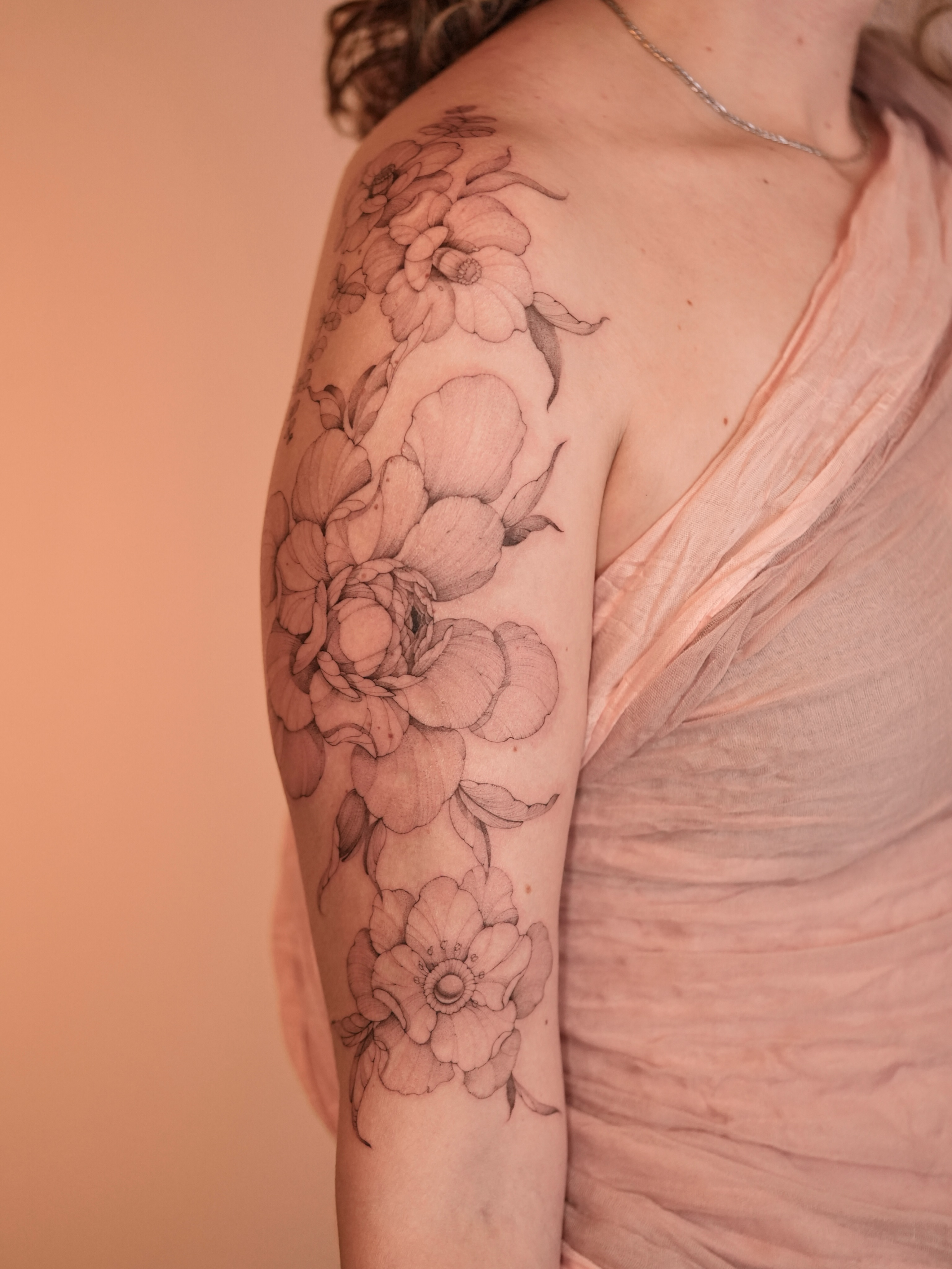Floral bouquet black and grey tattoo on the upper arm by Zalina Loriia