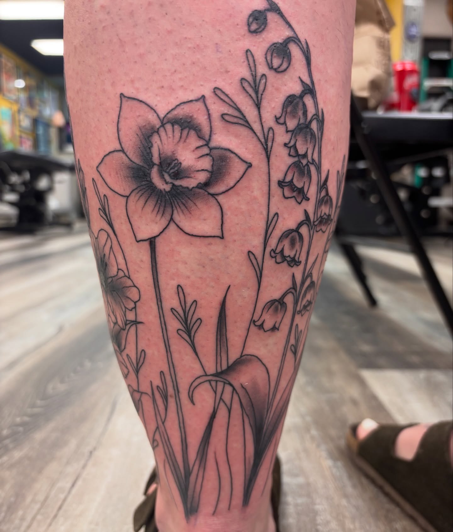 Daffodil and bellflowers black and grey tattoo on the calf by Megan