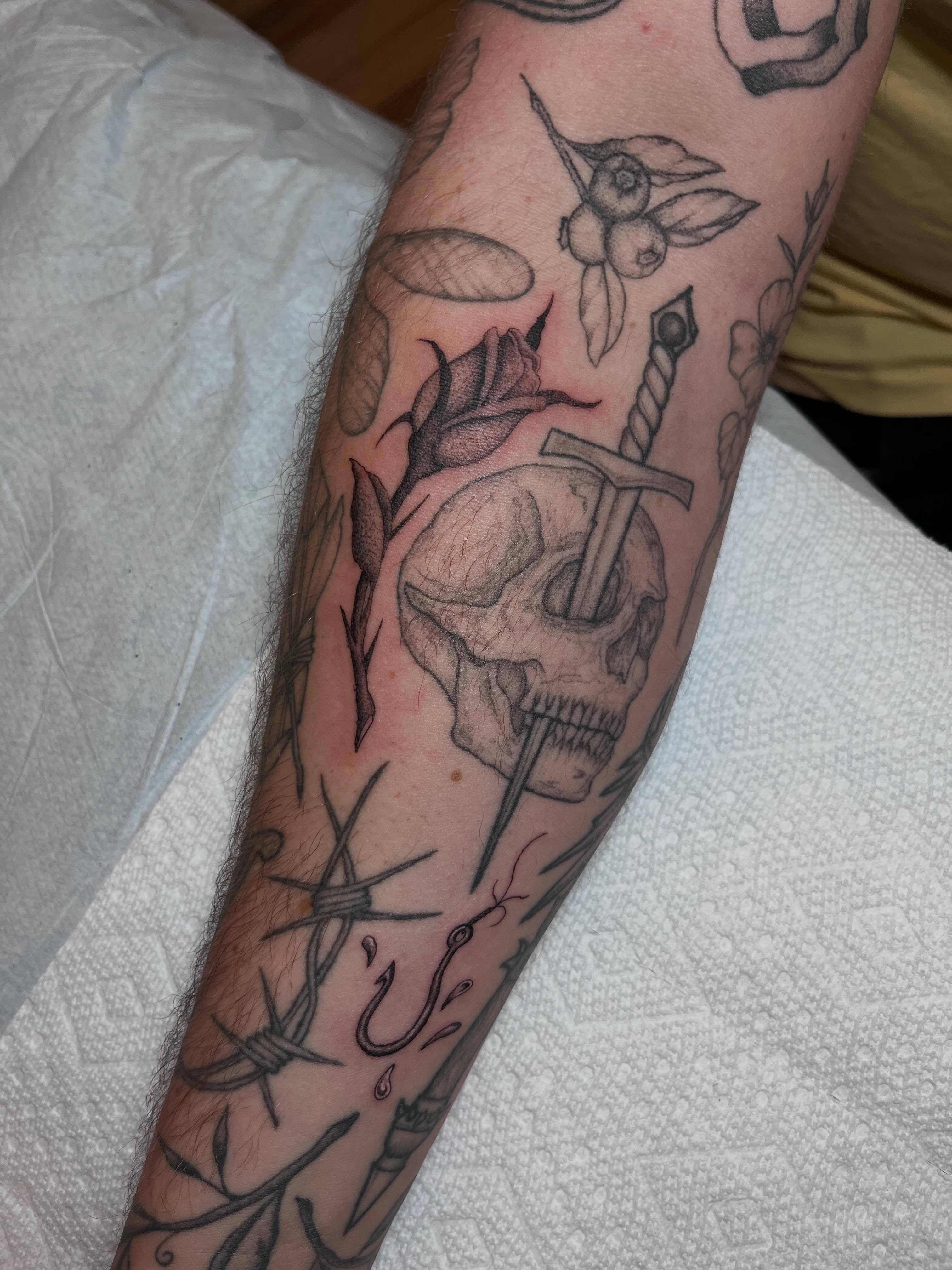 Skull with sword realism tattoo on the forearm by Jackson Kirchhoff