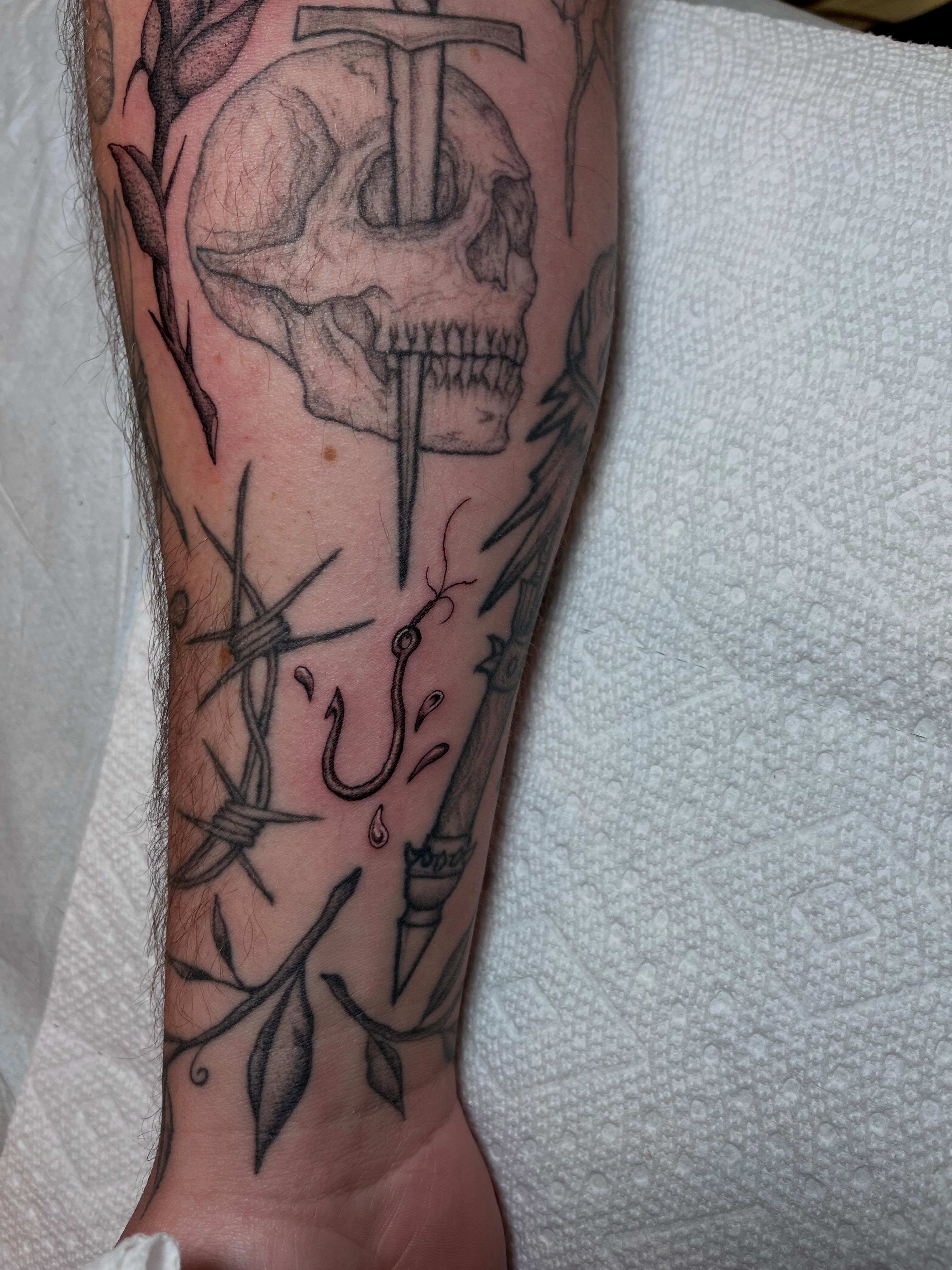 Skull with sword realism tattoo on the forearm by Jackson Kirchhoff