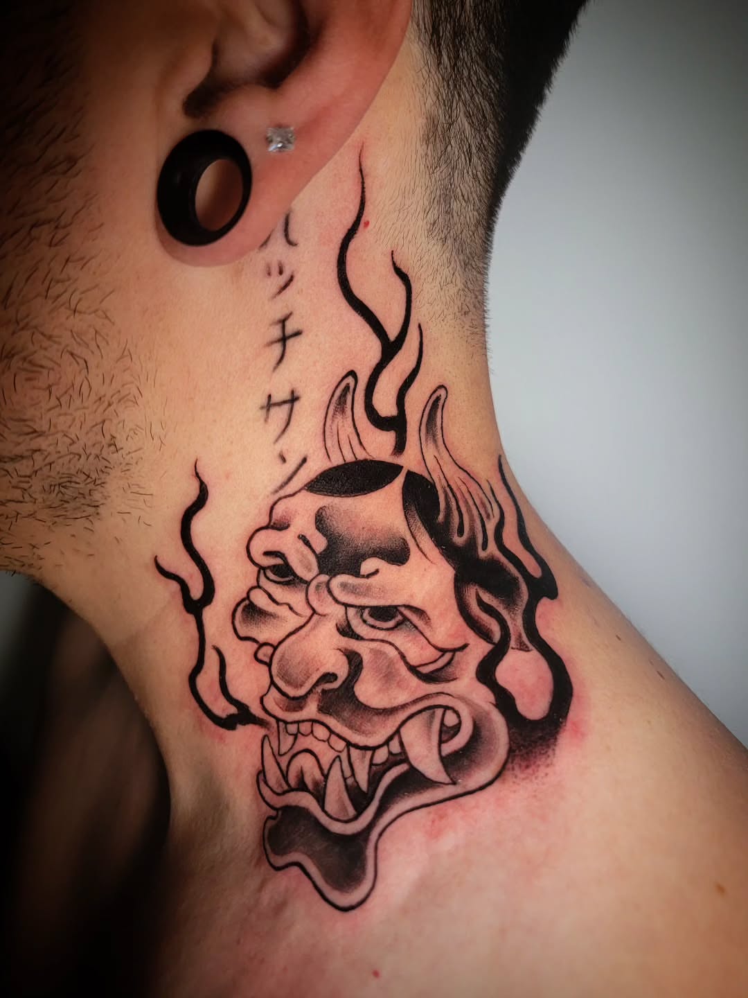 Demon mask black and grey tattoo on the neck by Randyz Tattyz