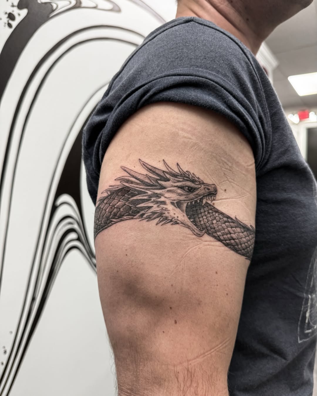 Dragon black and grey tattoo on the upper arm by Brows & Tattoos