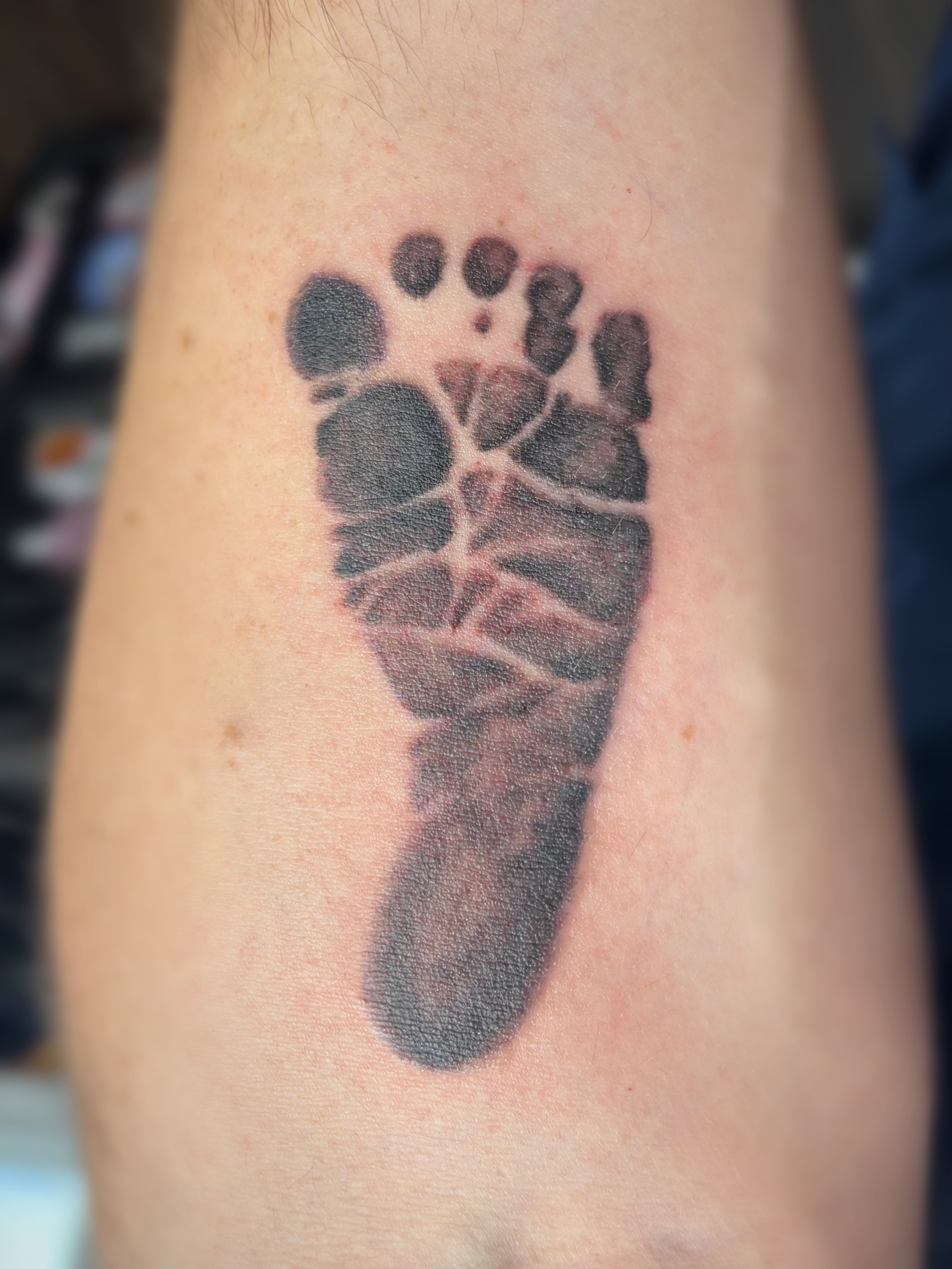 Footprint black and grey tattoo on the forearm by Bree Burgess
