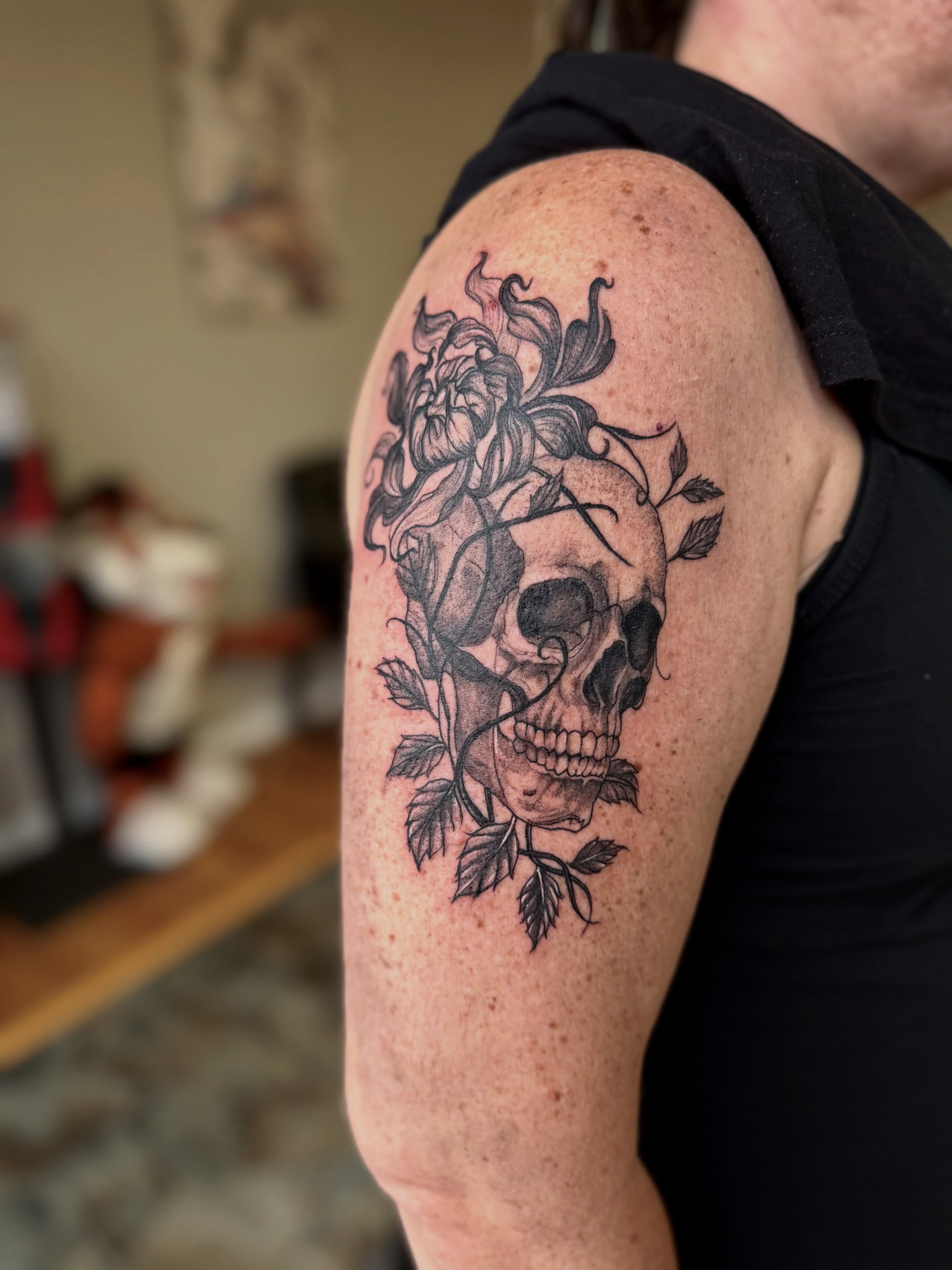 Skull and flowers realism tattoo on the shoulder by Skylar Sheeley