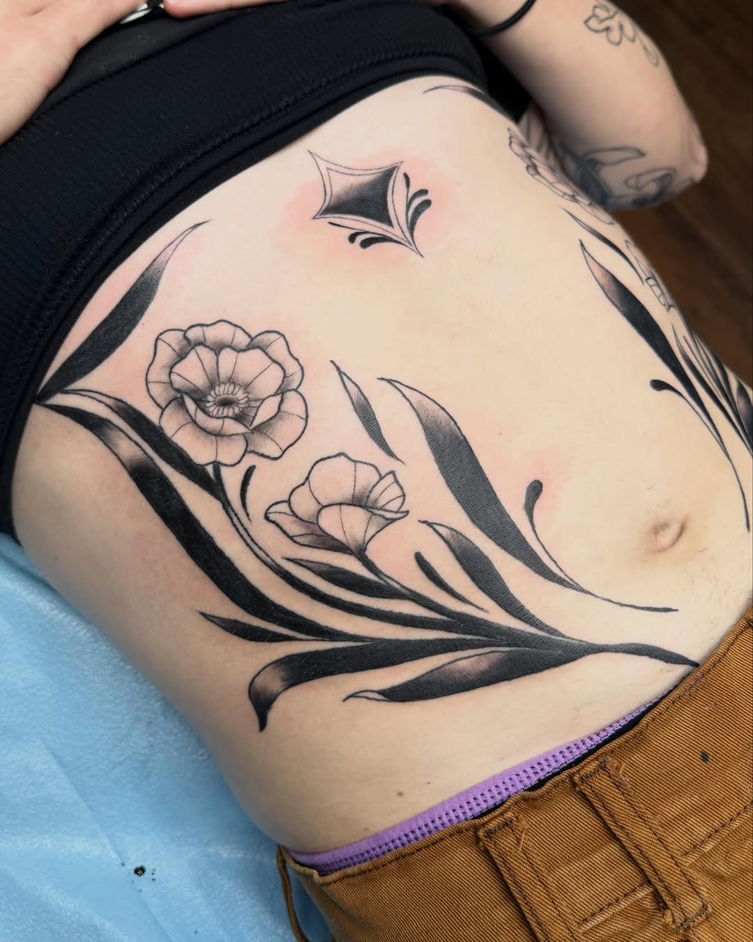Floral design with geometric accent fine line tattoo on the ribs by Bri ⚡️✨