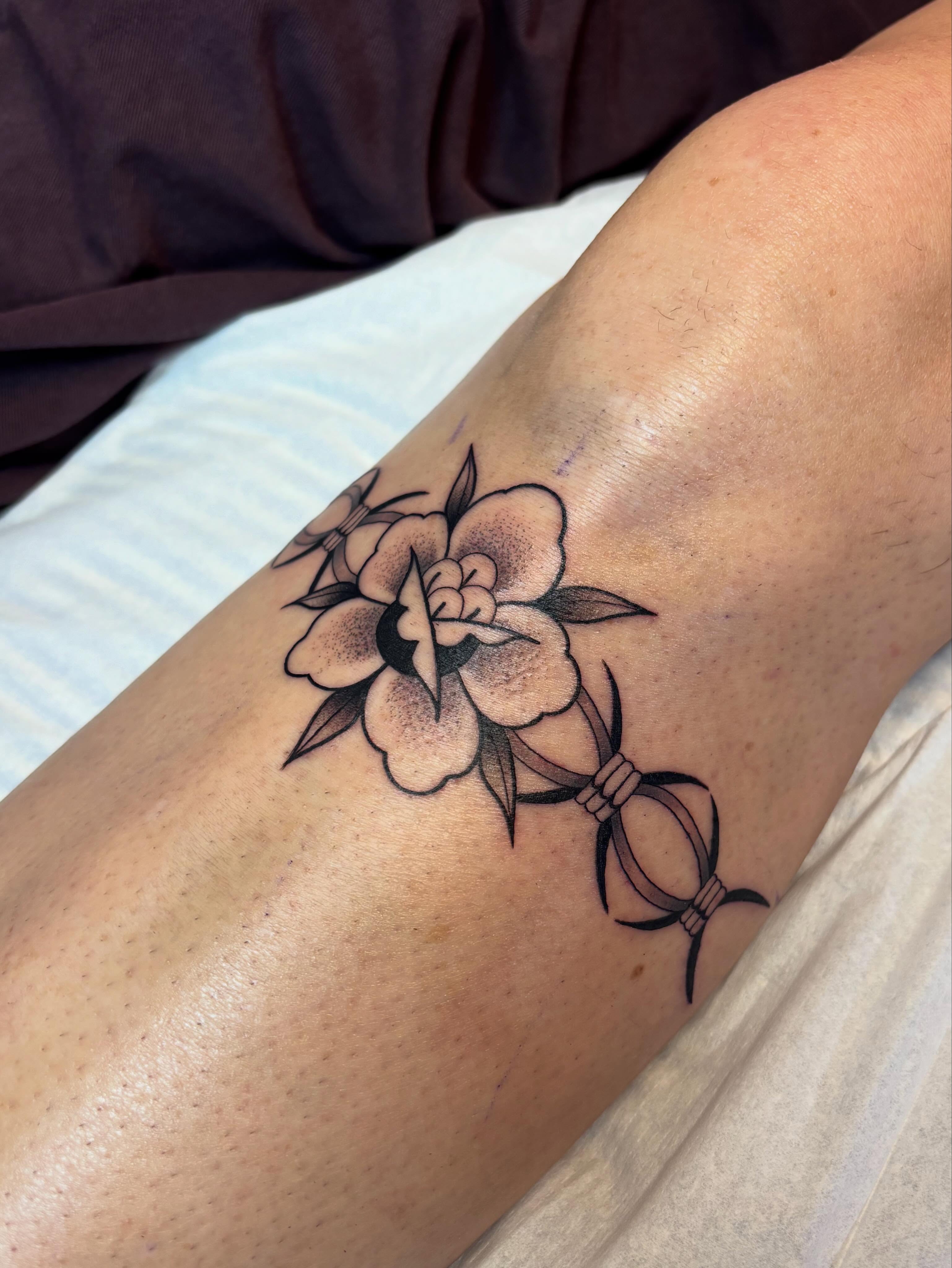 Flower and ribbon black and grey tattoo on the forearm by Victoria Bacon