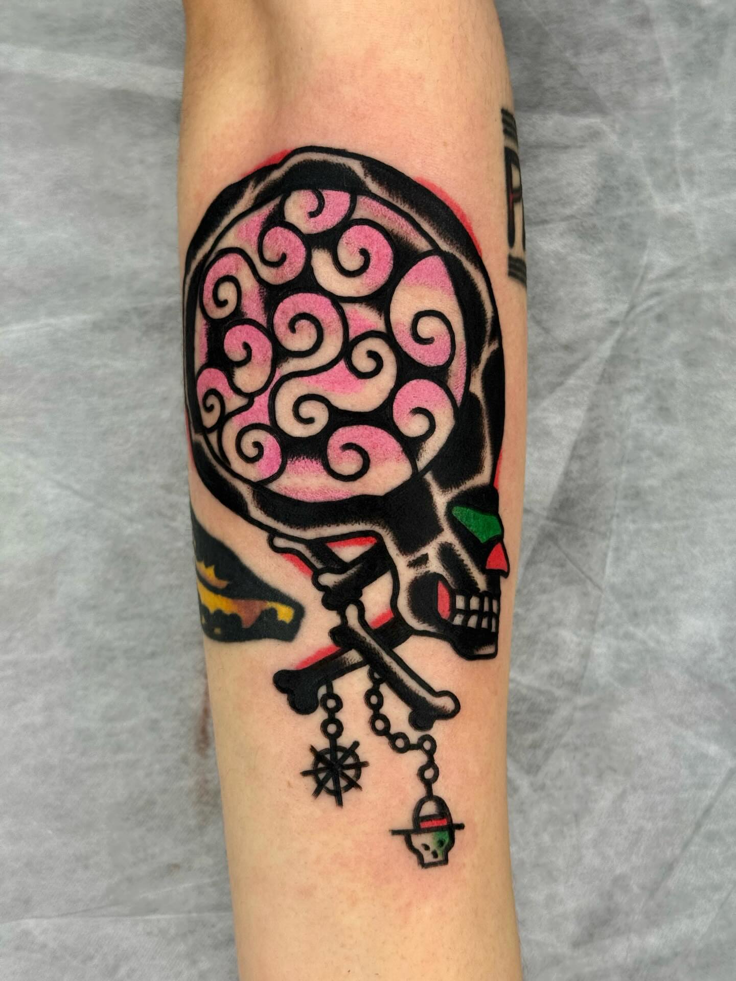 Skull with swirling brain American traditional tattoo on the forearm by JAX