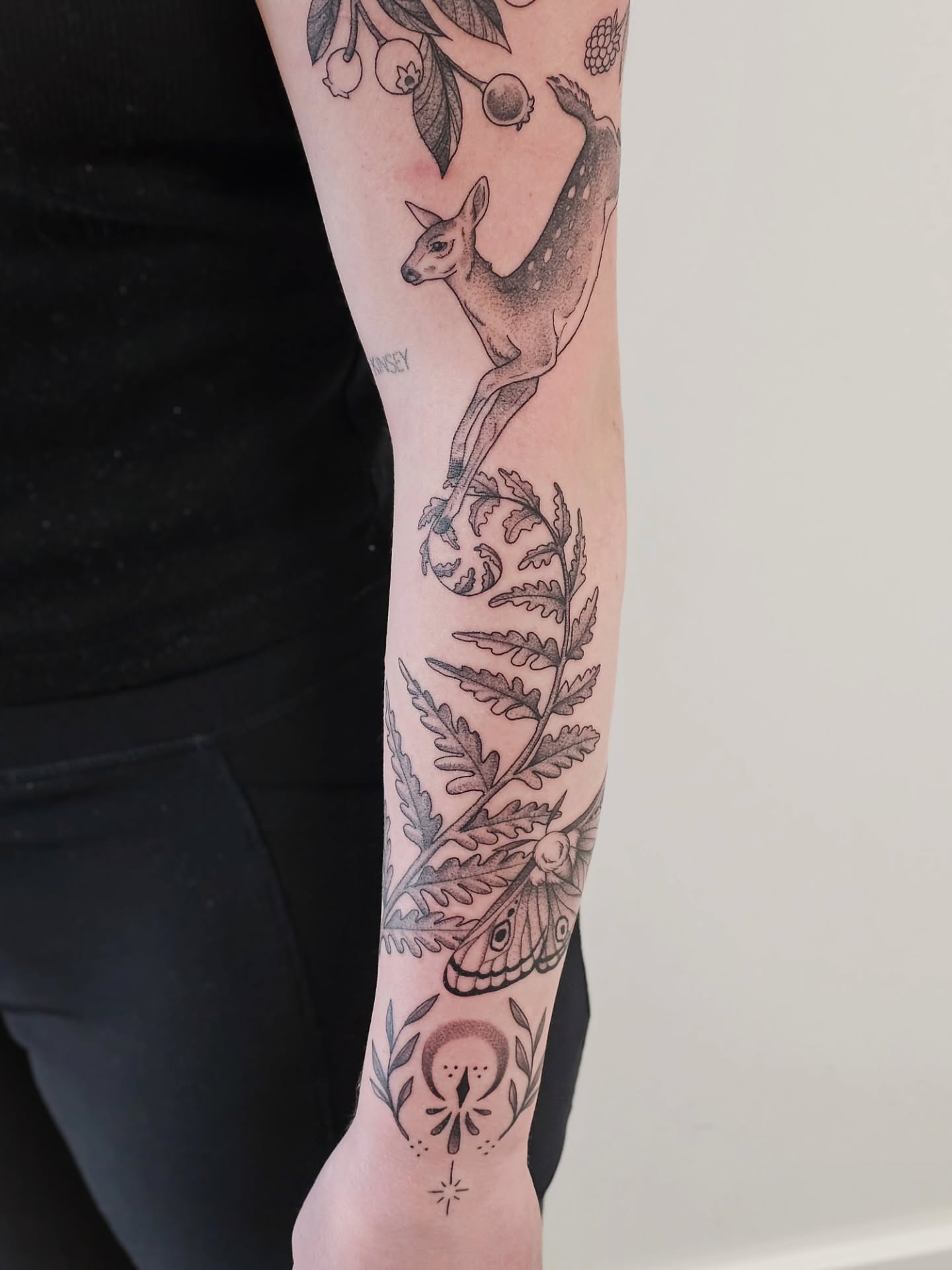 Deer and fern dotwork tattoo on the forearm by Kylie Lund