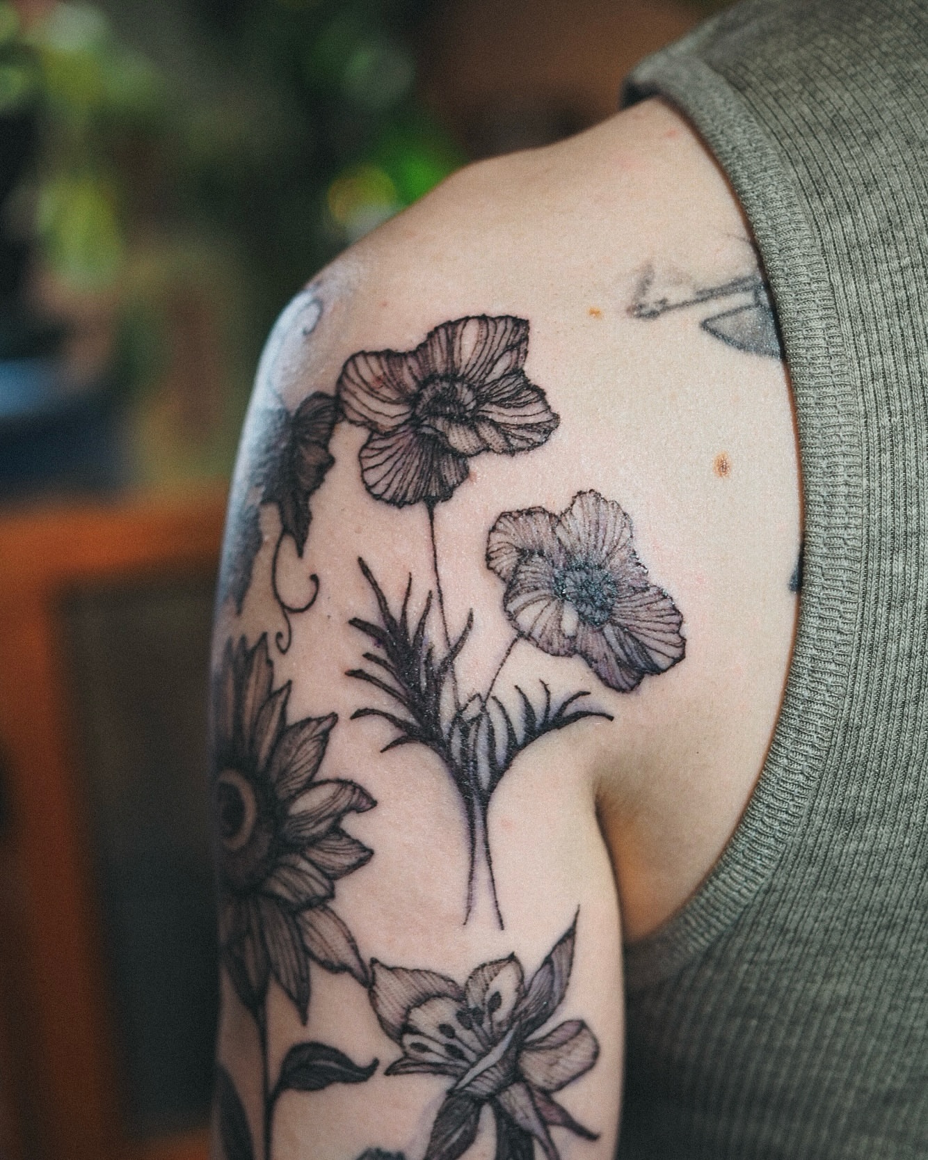 Flowers black and grey tattoo on the upper arm by Inks by Nastia