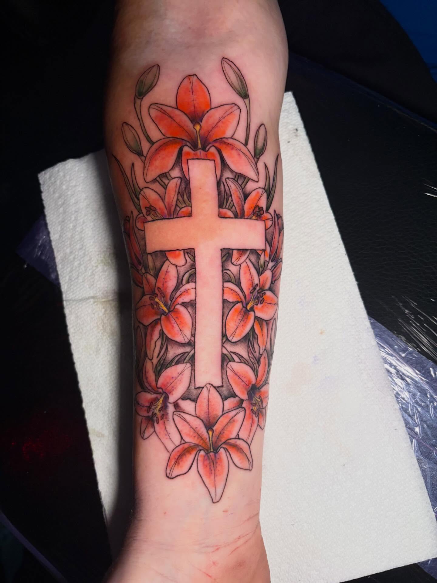 Cross with lilies realism tattoo on the forearm by Fredrick Tigerman